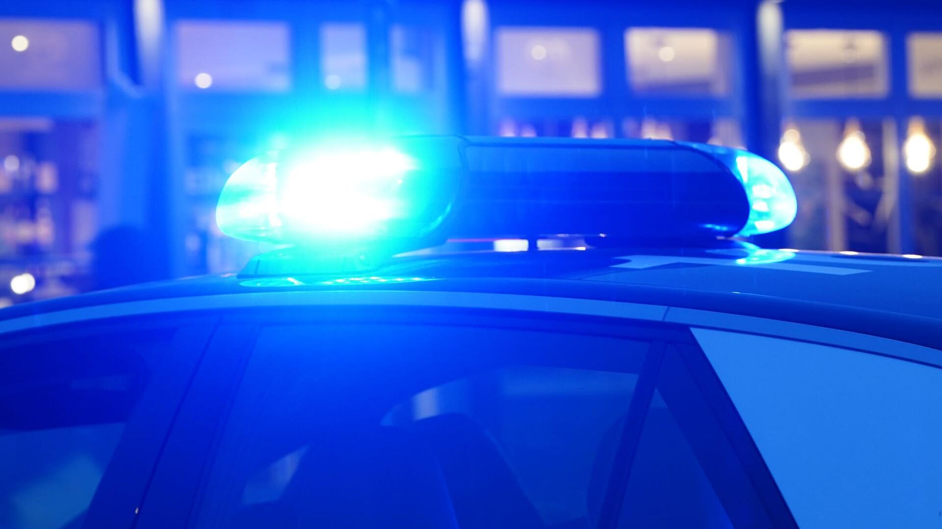 Ein Streifenwagen der Polizei steht mit eingeschaltetem Blaulicht an einem Einsatzort. 