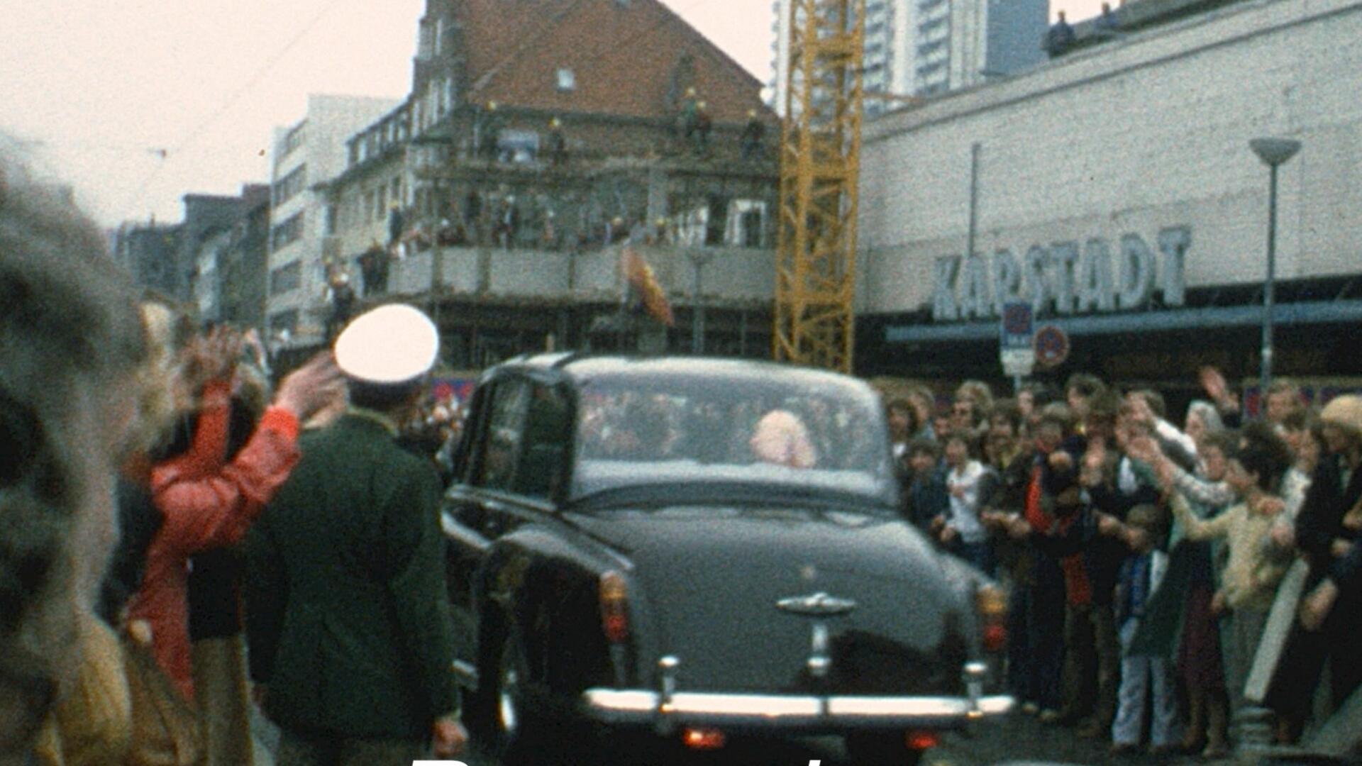 Foto stammt aus den 60er Jahren und zeigt ein Auto, umsäumt von jubelnden Menschen. 