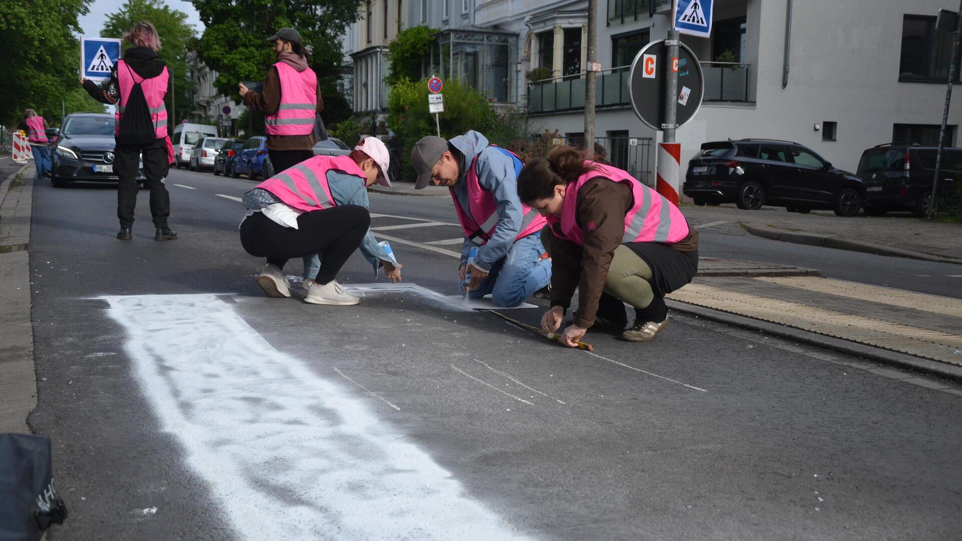 Fabian Beese (Zweiter von rechts) sprüht mit weiteren Aktivisten mit weißer Farbe einen illegalen Zebrastreifen auf den Bremer Osterdeich.