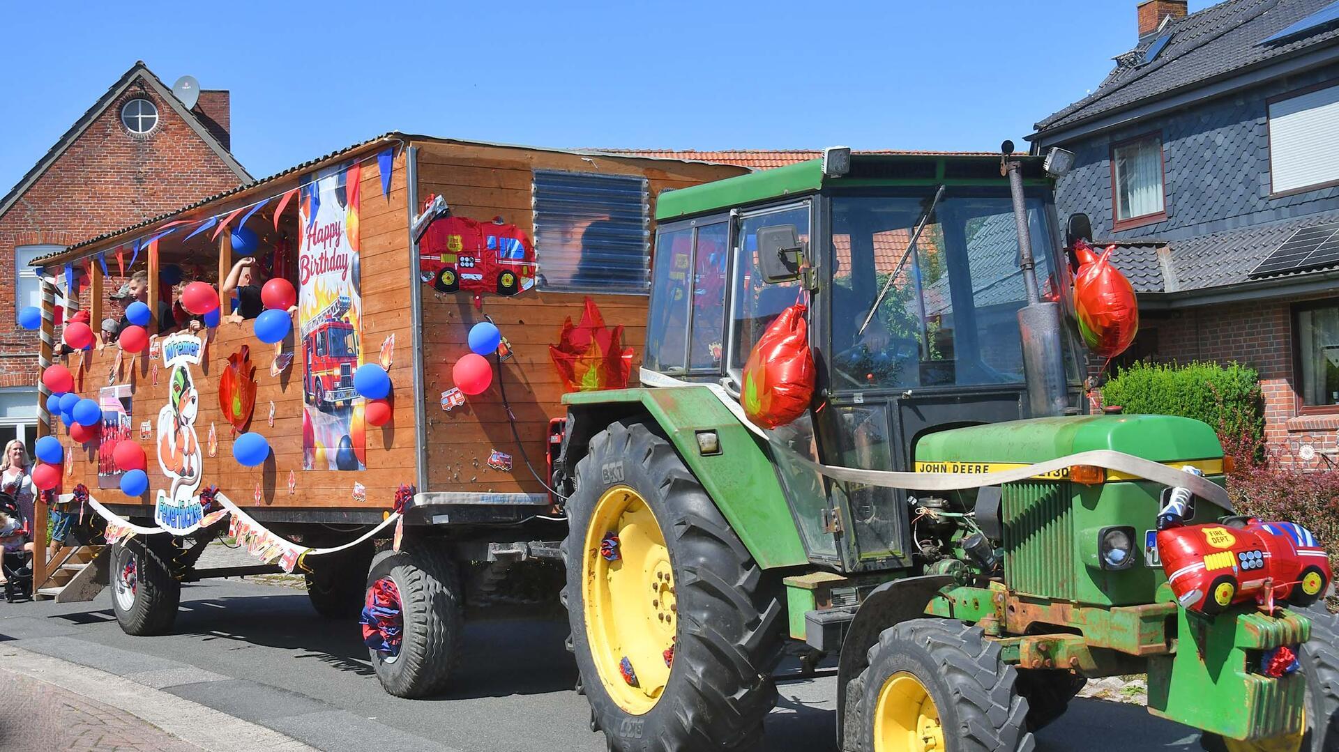 Ein Trecker zieht einen mit Luftballons geschmückten Anhänger