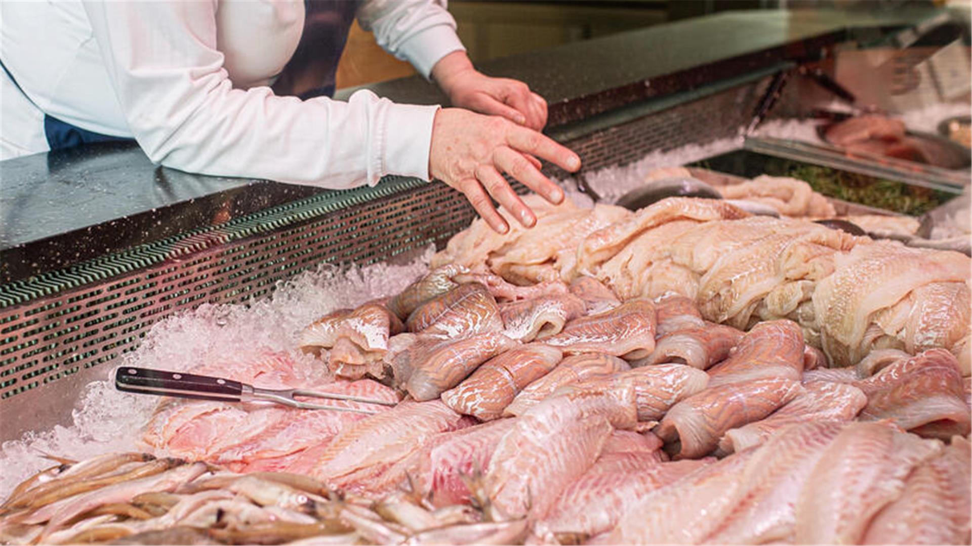 Eine Mitarbeiterin zeigt Ware in einem Fischgeschäft.