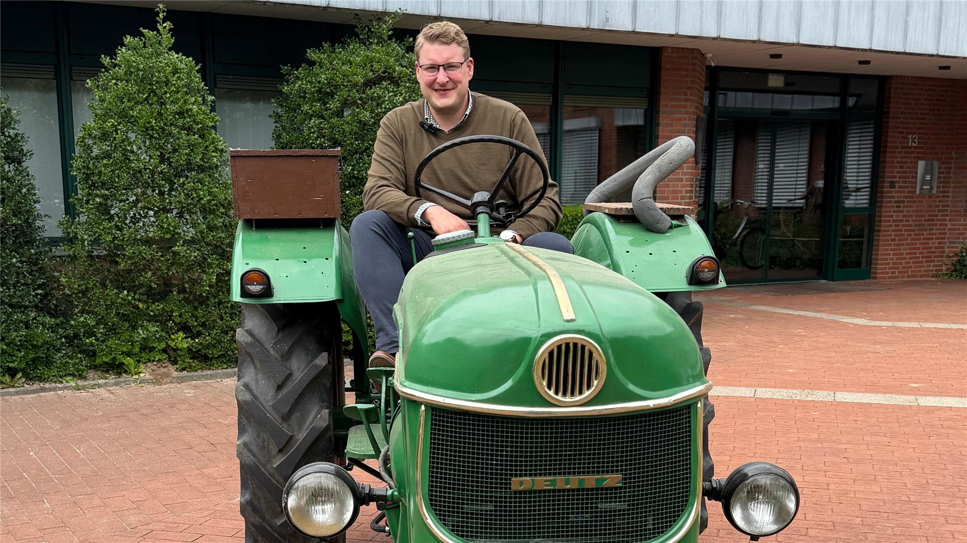 Bürgermeister Henrik Wärner sitzt auf einem Oldtimer-Trecker vor dem Rathaus Schiffdorf.