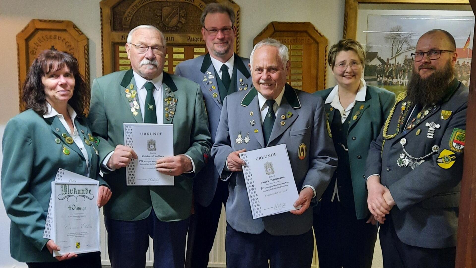 Gruppenfoto von Mitgliedern des Schützenvereins Spaden in Uniform bei der Jahreshauptversammlung, einige Geehrte halten Urkunden für langjährige Mitgliedschaft.