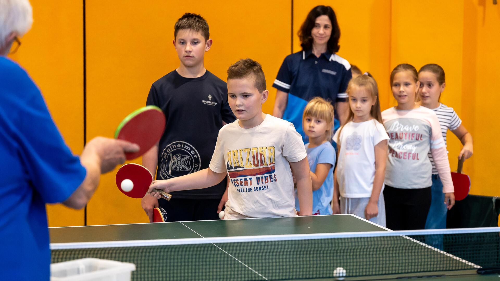 Kinder spielen Tischtennis. 
