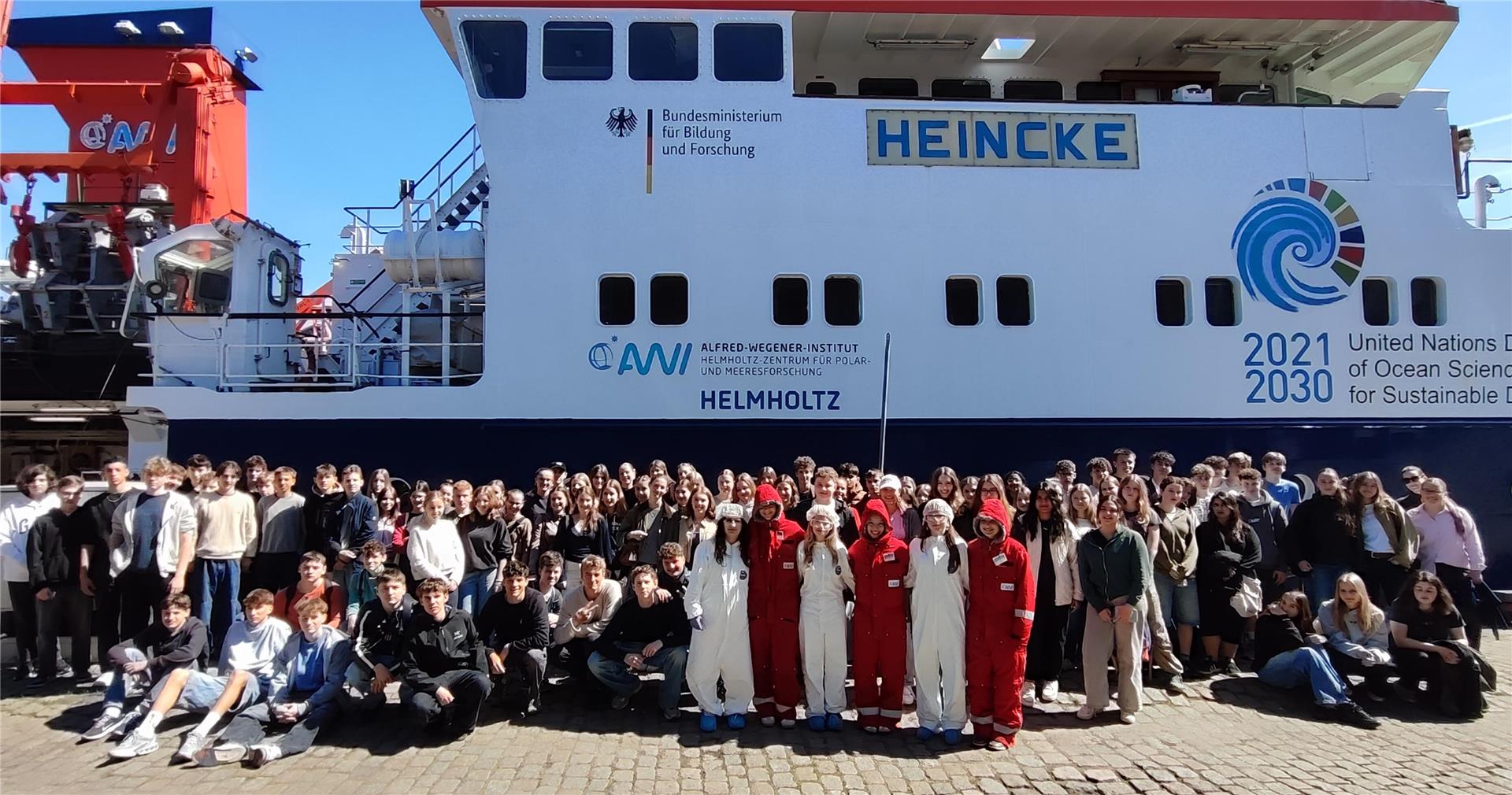 Gruppenfoto von rund 200 Schülerinnen und Schülern vor dem Forschungsschiff "Heincke" des Alfred-Wegener-Instituts in Bremerhaven bei sonnigem Wetter.