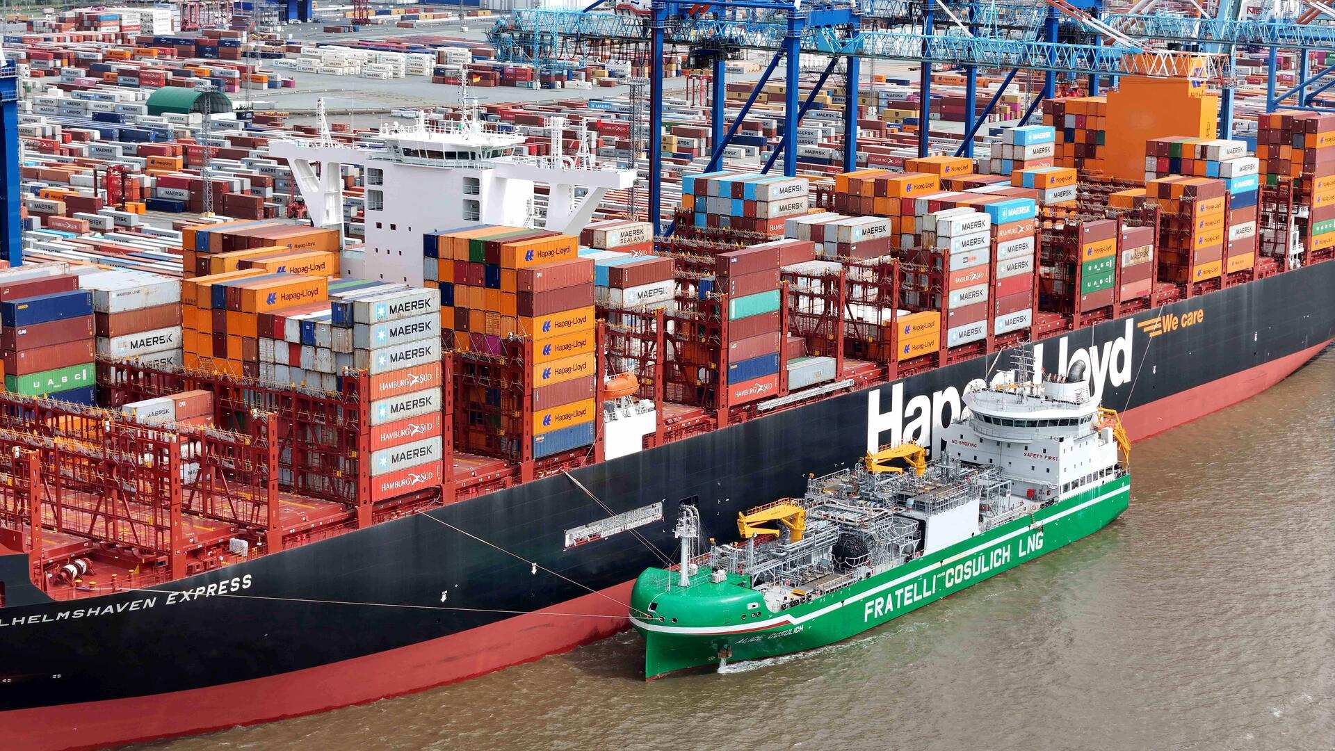 Ein kleines Bunkerschiff liegt neben einem großen Containerschiff