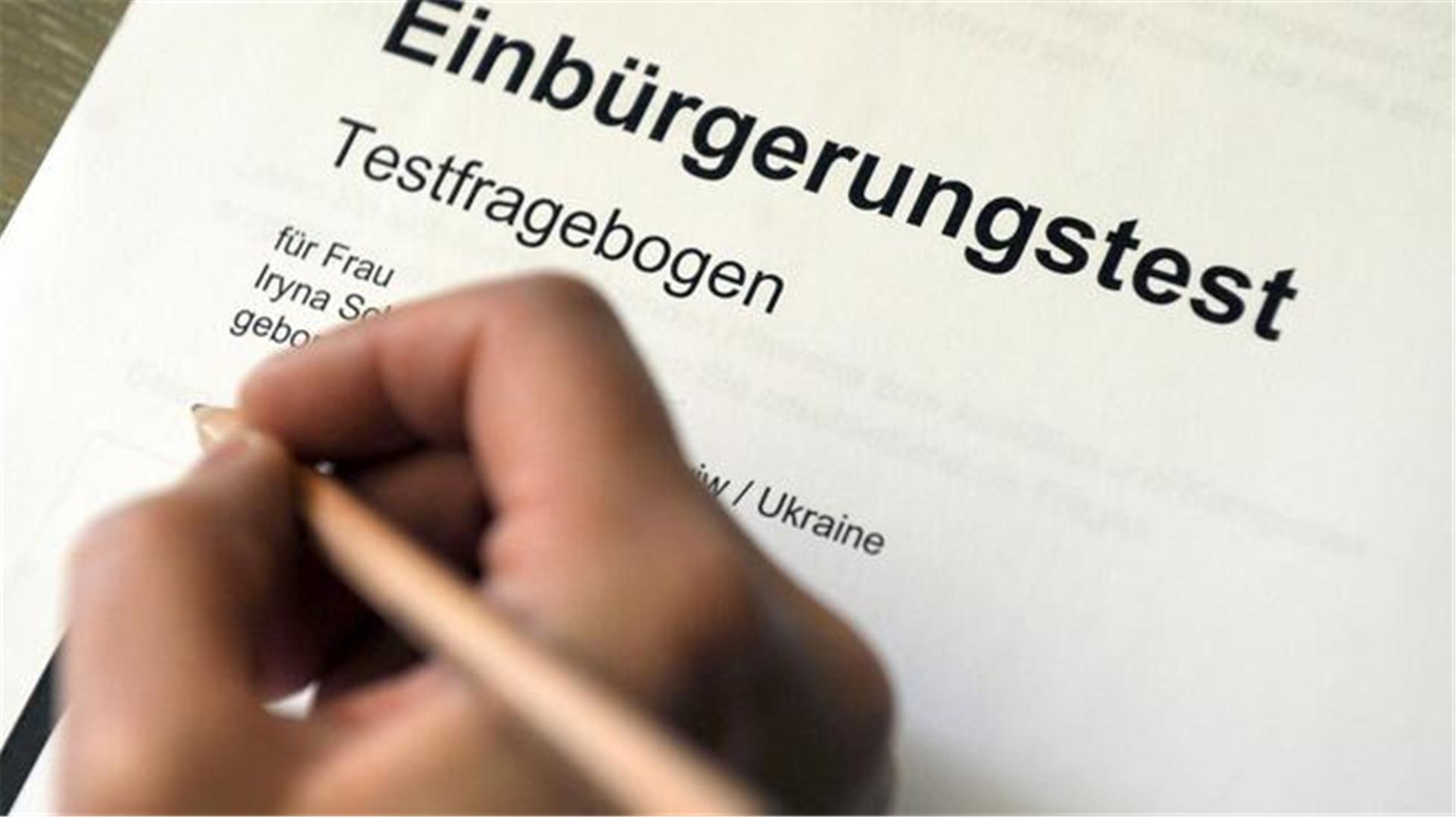 Eine Hand mit einem Bleistift auf dem Testfragebogen Einbürgerungstest. 