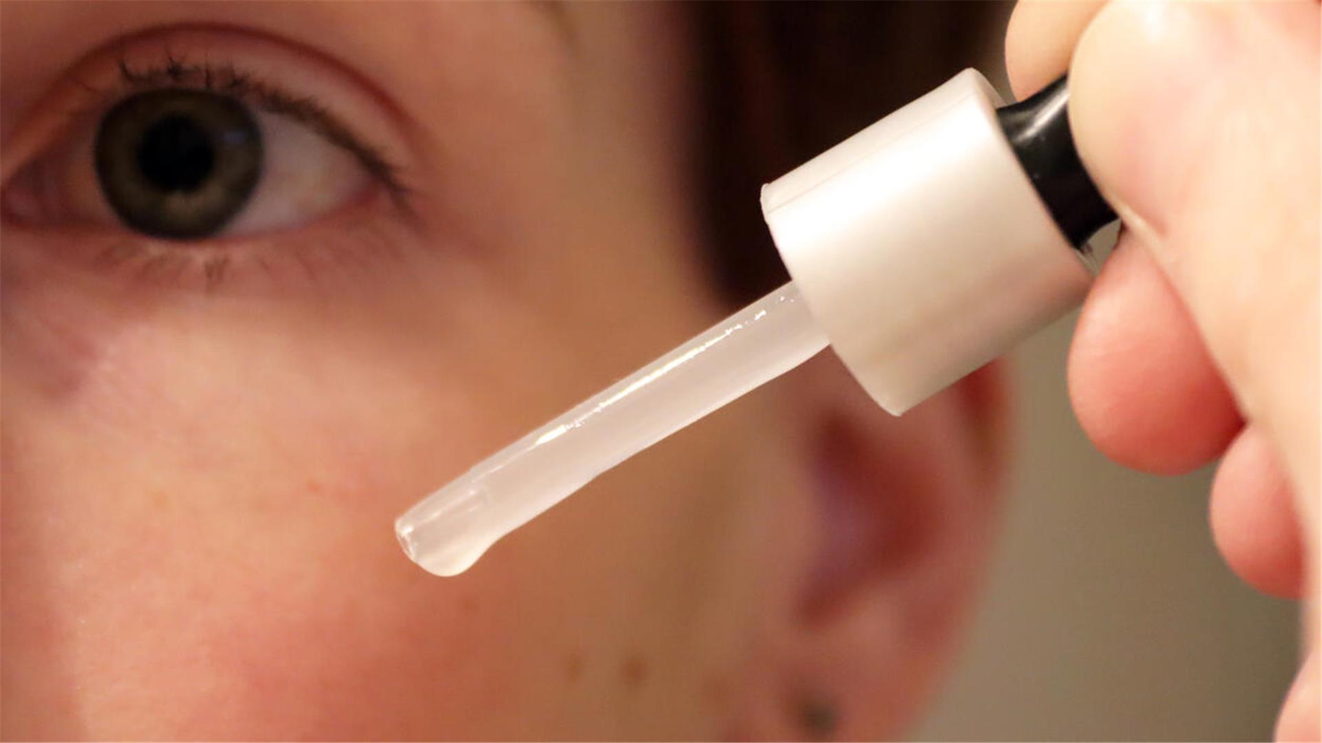 Gesicht und Pipette mit Flüssigkeit