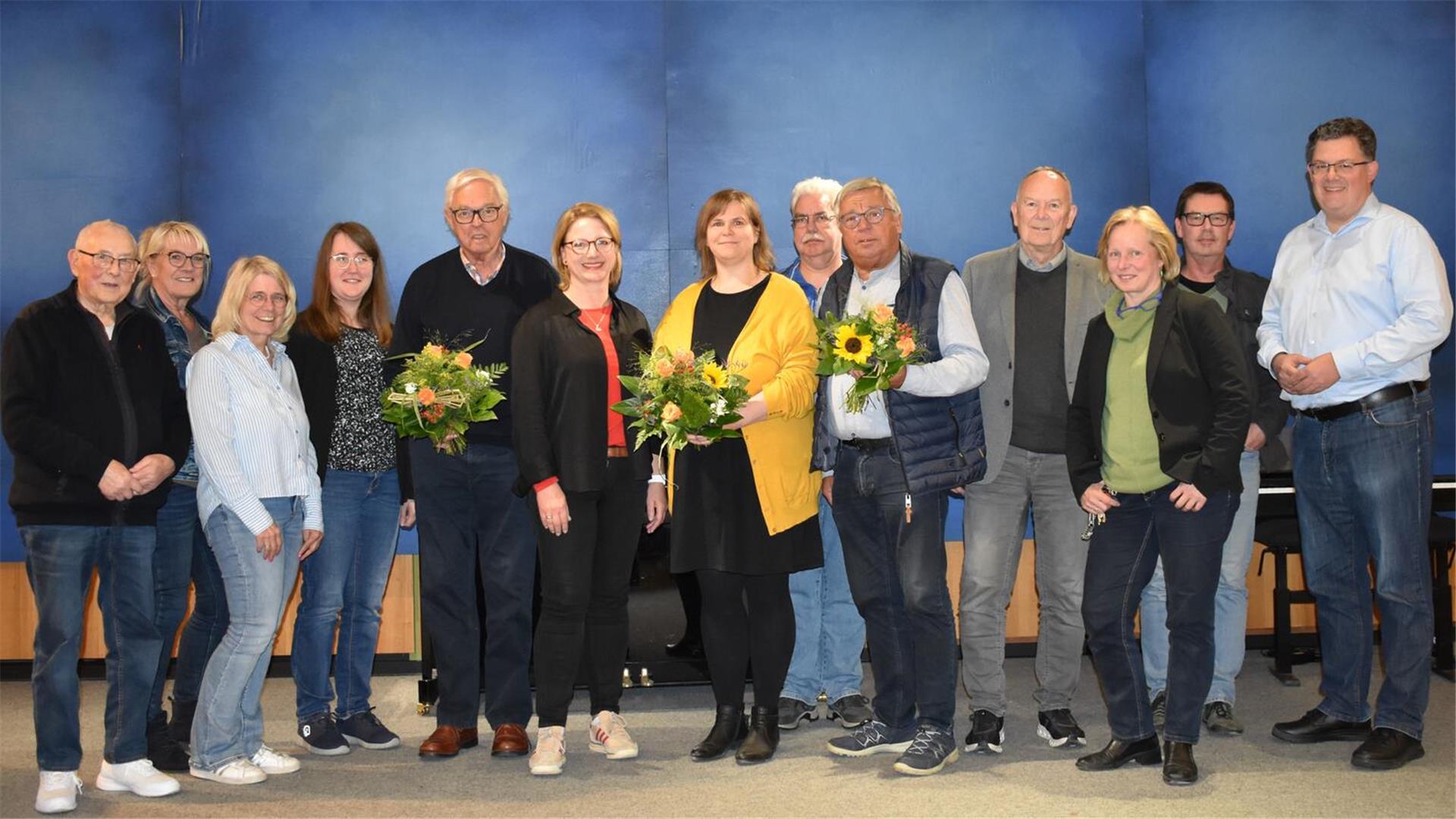Gruppenfoto mit Mitgliedern der Kontaktstelle Musik im Landkreis Rotenburg, darunter der scheidende und der neue Vorstand. Mehrere Personen halten Blumensträuße in den Händen.