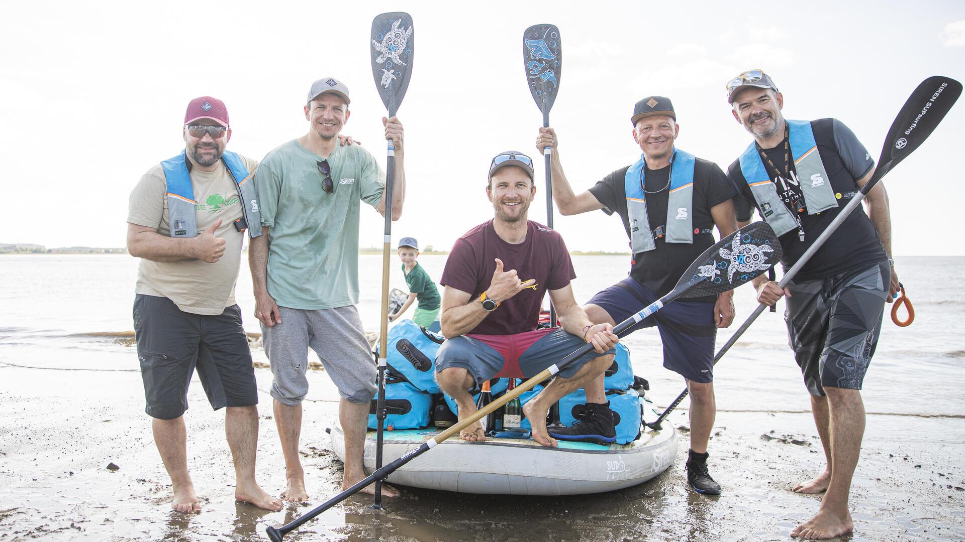 Fünf Männer und ein Stand-up-Paddleboard.
