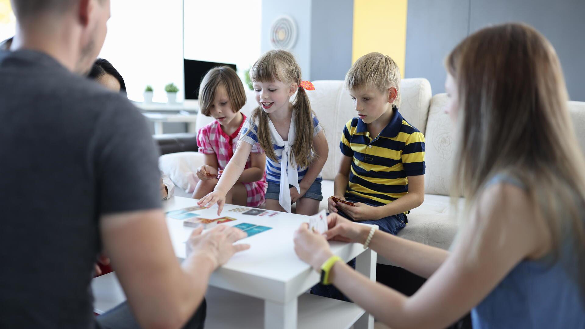 Kinder und Erwachsene spielen ein Brettspiel.