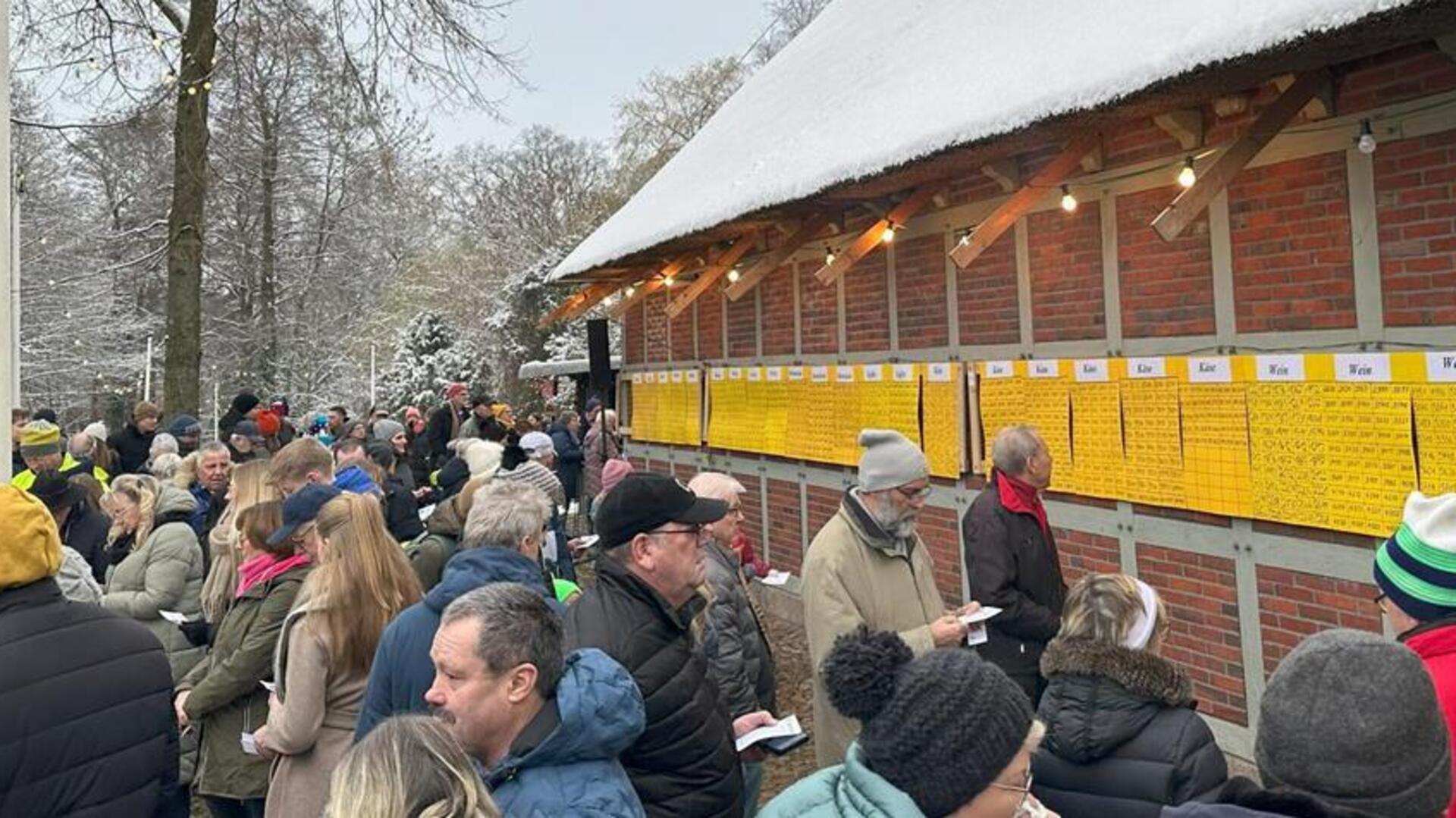 Menschen stehen an einem alten Gebäude und vergleichen an gelben Tafeln, ob sie bei der Lotterie gewonnen haben. 