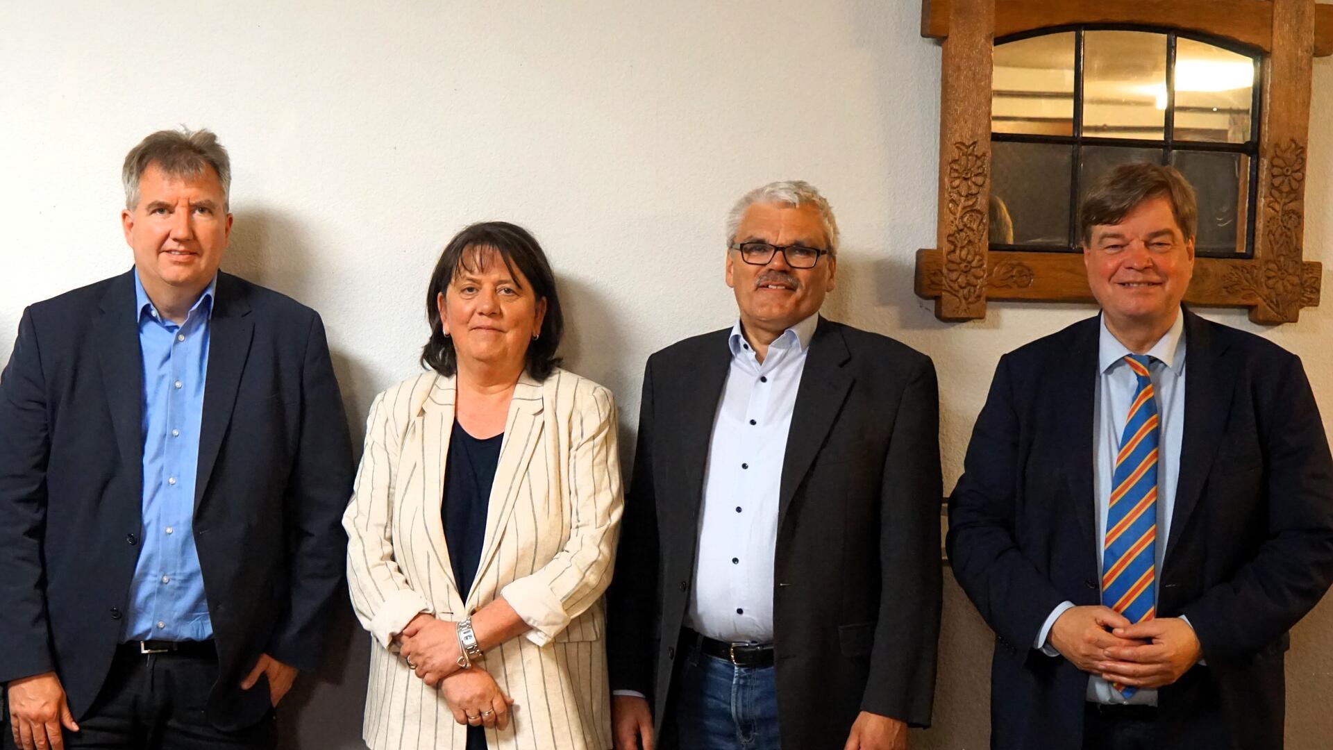 Drei Männer und eine Frau stehen nebeneinander  