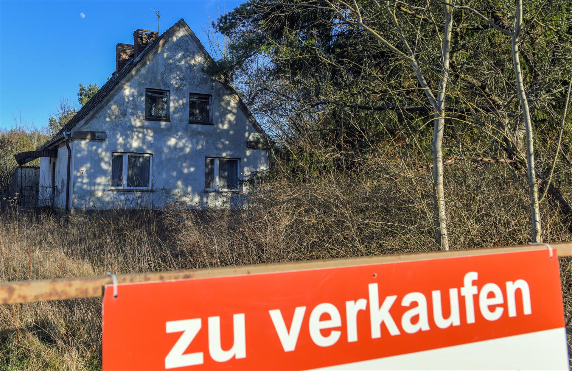 Ein Schild mit der Aufschrift «zu verkaufen» steht auf einem Grundstück mit einem Einfamilienhaus. 