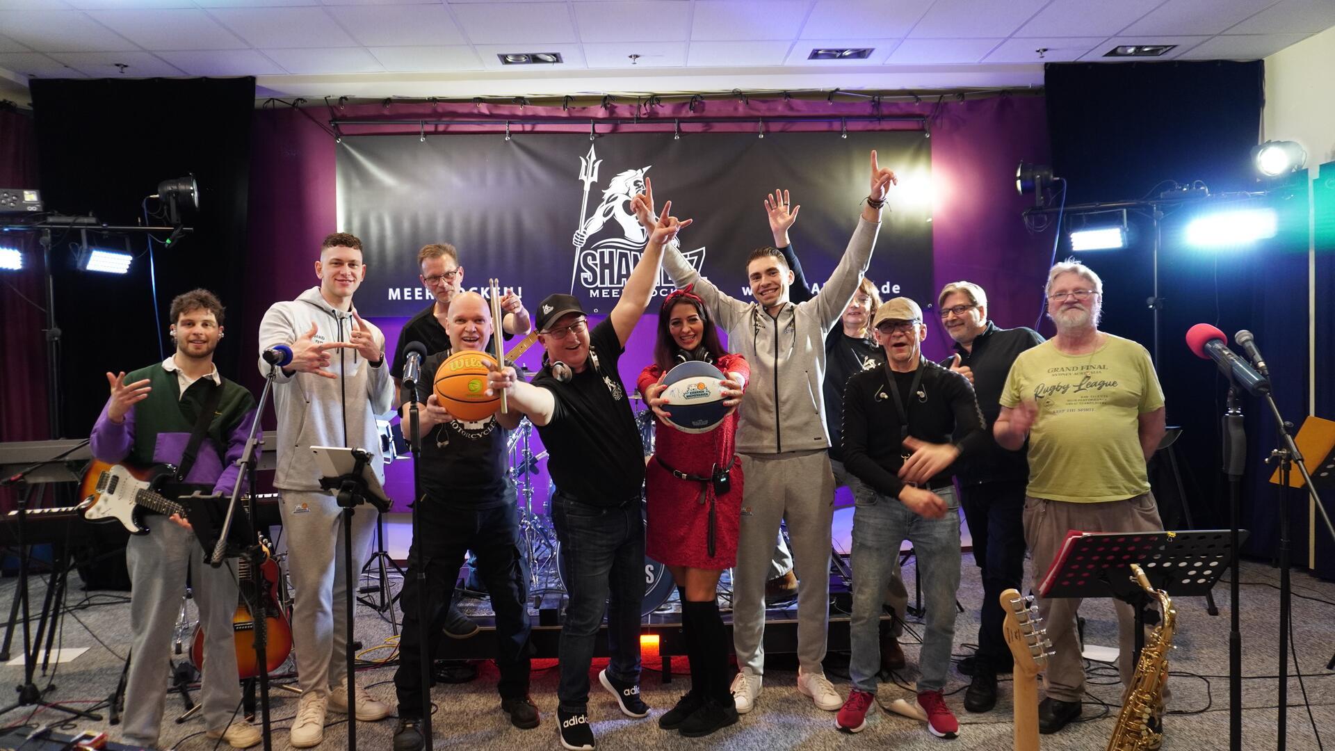 Mitglieder der Gruppe Shanteez in ihrem Proberaum. Einige von ihnen halten Basketbälle in der Hand. Die Band wird in der Halbzeitpause bei einem Spiel der Eisbären Bremerhaven spielen.