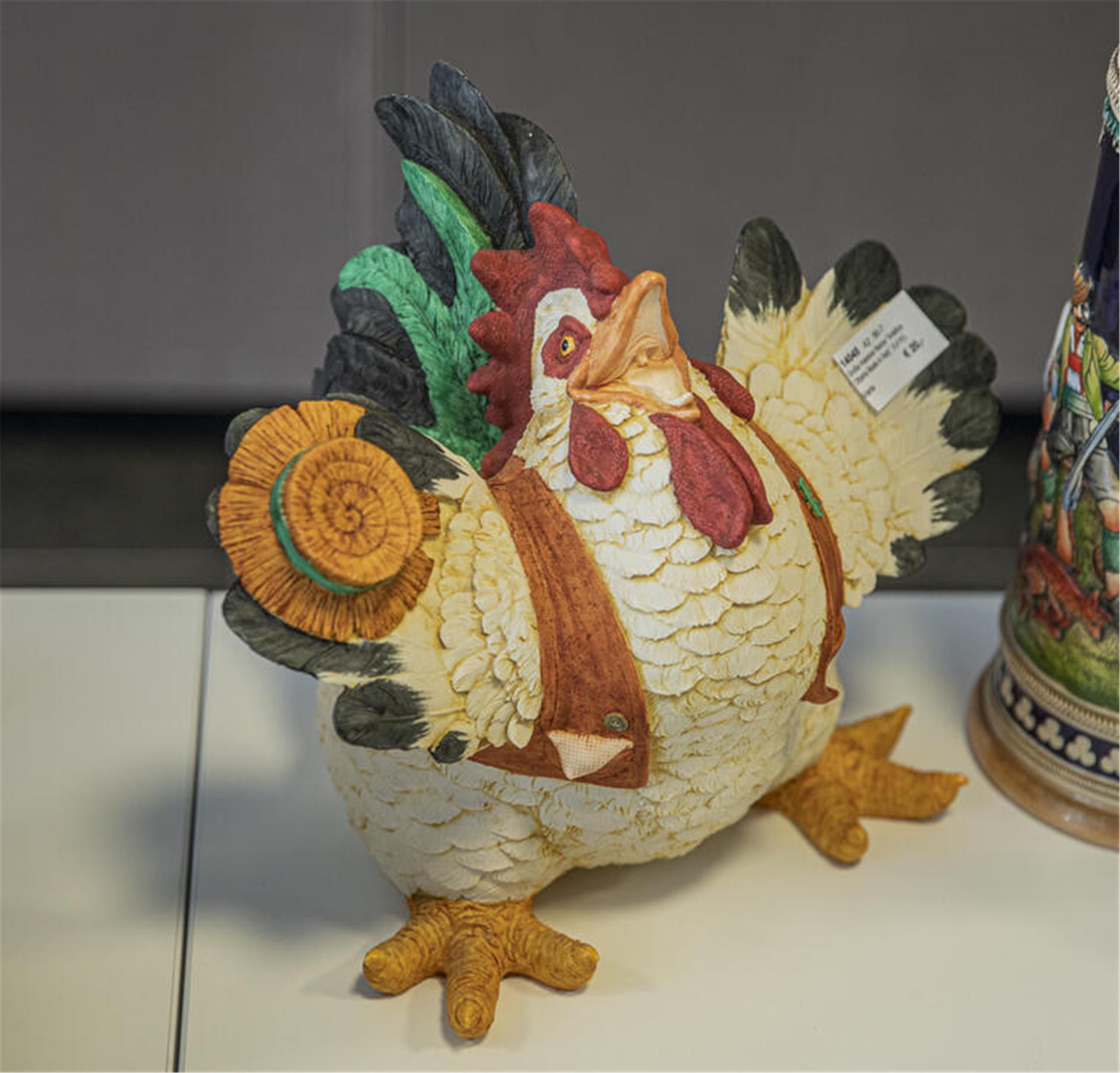 Porzellan-Henne mit Hut und breitem Grinsen.