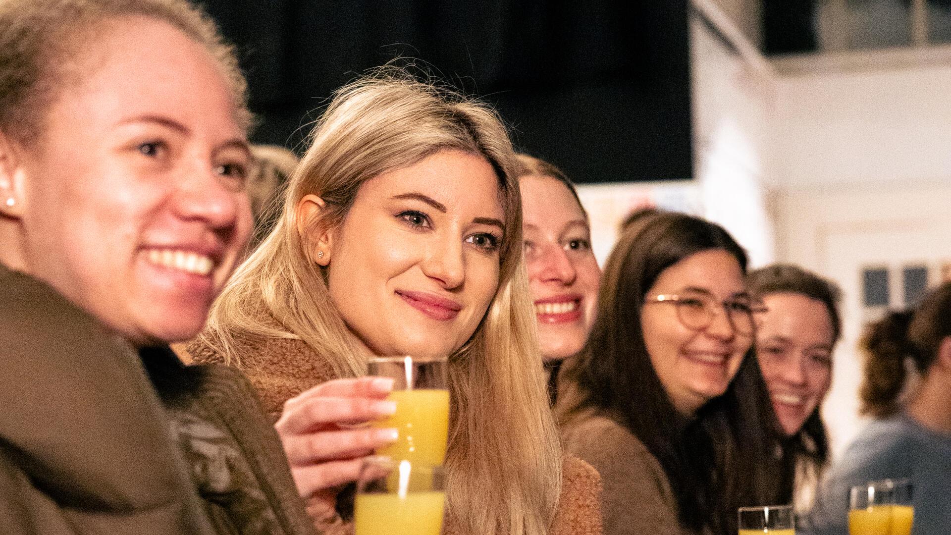 Mehrere Personen prosten sich mit einem Glas Organgensaft zu.