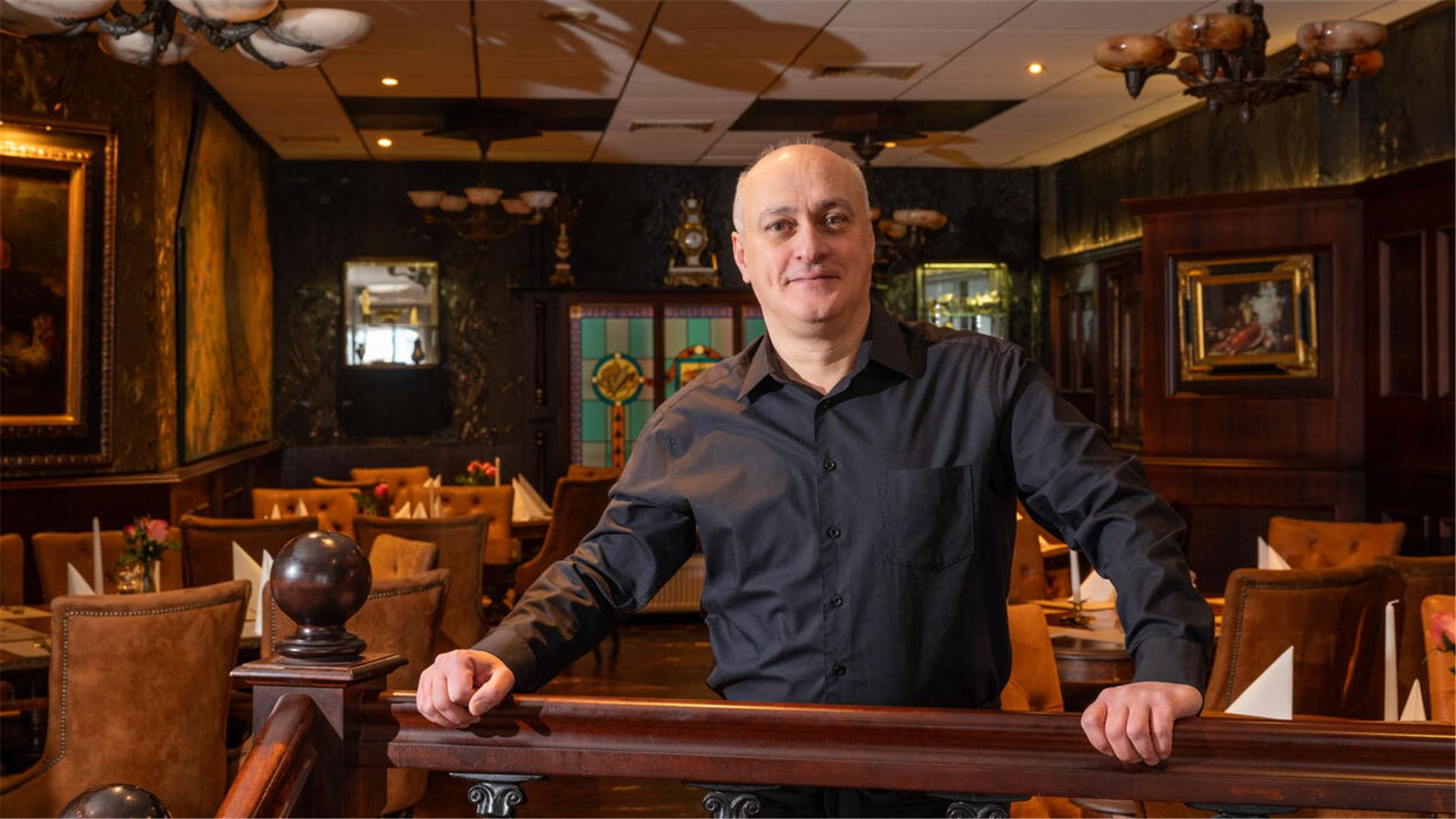 Ein Mann steht in einem Restaurant und lehnt an einem Geländer