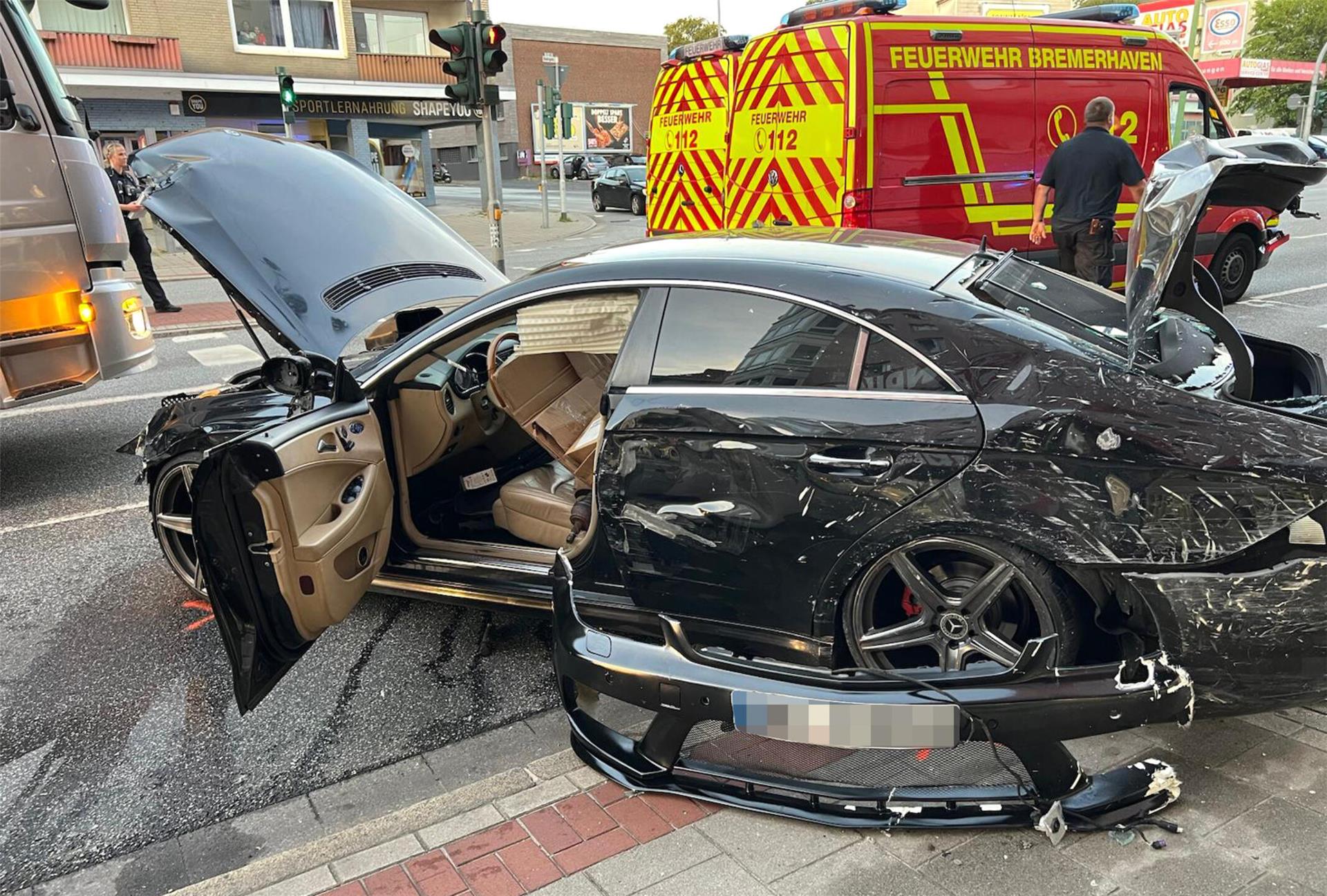 Ein kaputtes Auto. Es ist schwarz und befindet sich auf einer Straße.