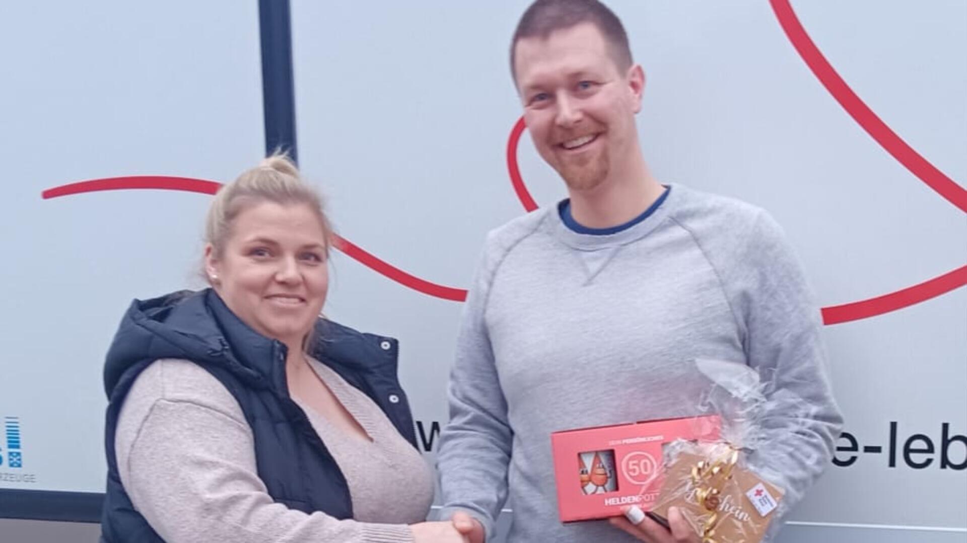 Eine Frau gratuliert einem Mann zur 50. Blutspende.