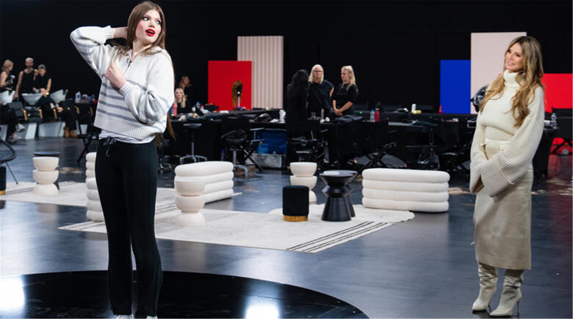 Eine Frau bewundert sich im Spiegel, eine andere schaut zu. Heidi Klum hat Xenia aus Loxstedt ein Umstyling verpasst bei GNTM.