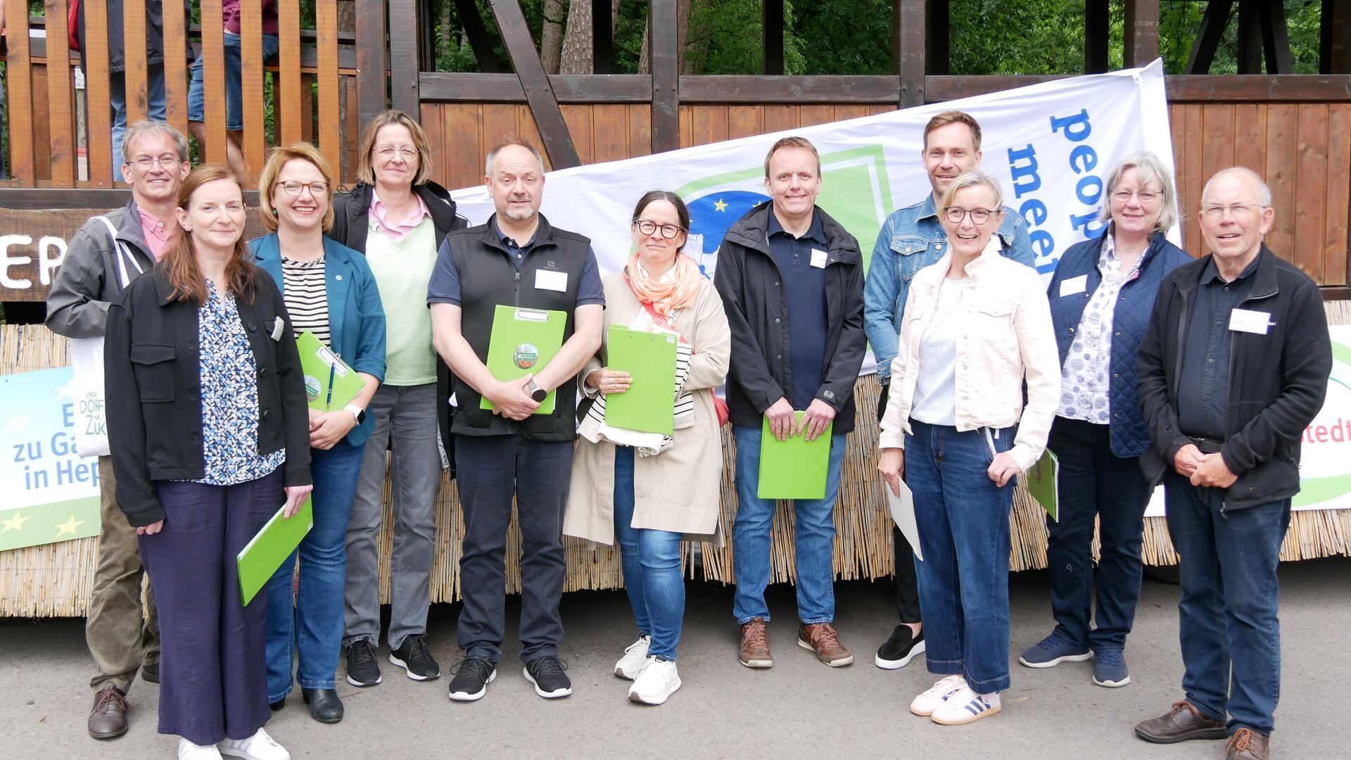 Heidi Stelljes (Dritte von rechts) und die Bezirkskommission des Wettbewerbs „Unser Dorf hat Zukunft“ vor dem Erntewagen der Landjugend.