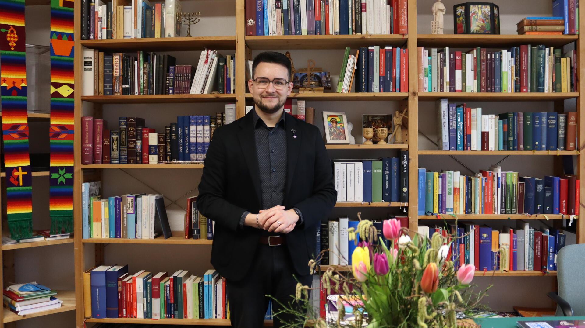 Mann in Anzug vor Bücherregal