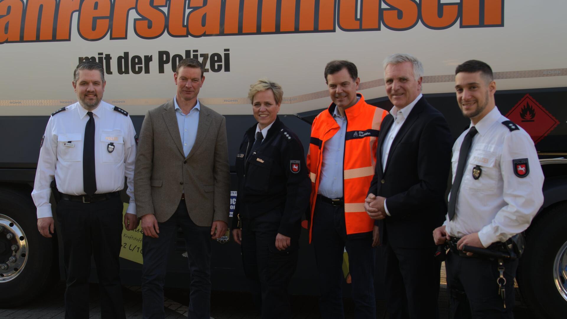 Fünf Männer und in der Bildmitte eine Frau stehen vor einem Lkw mit der Aufschrift "Fernfahrerstammtisch der Polizei".