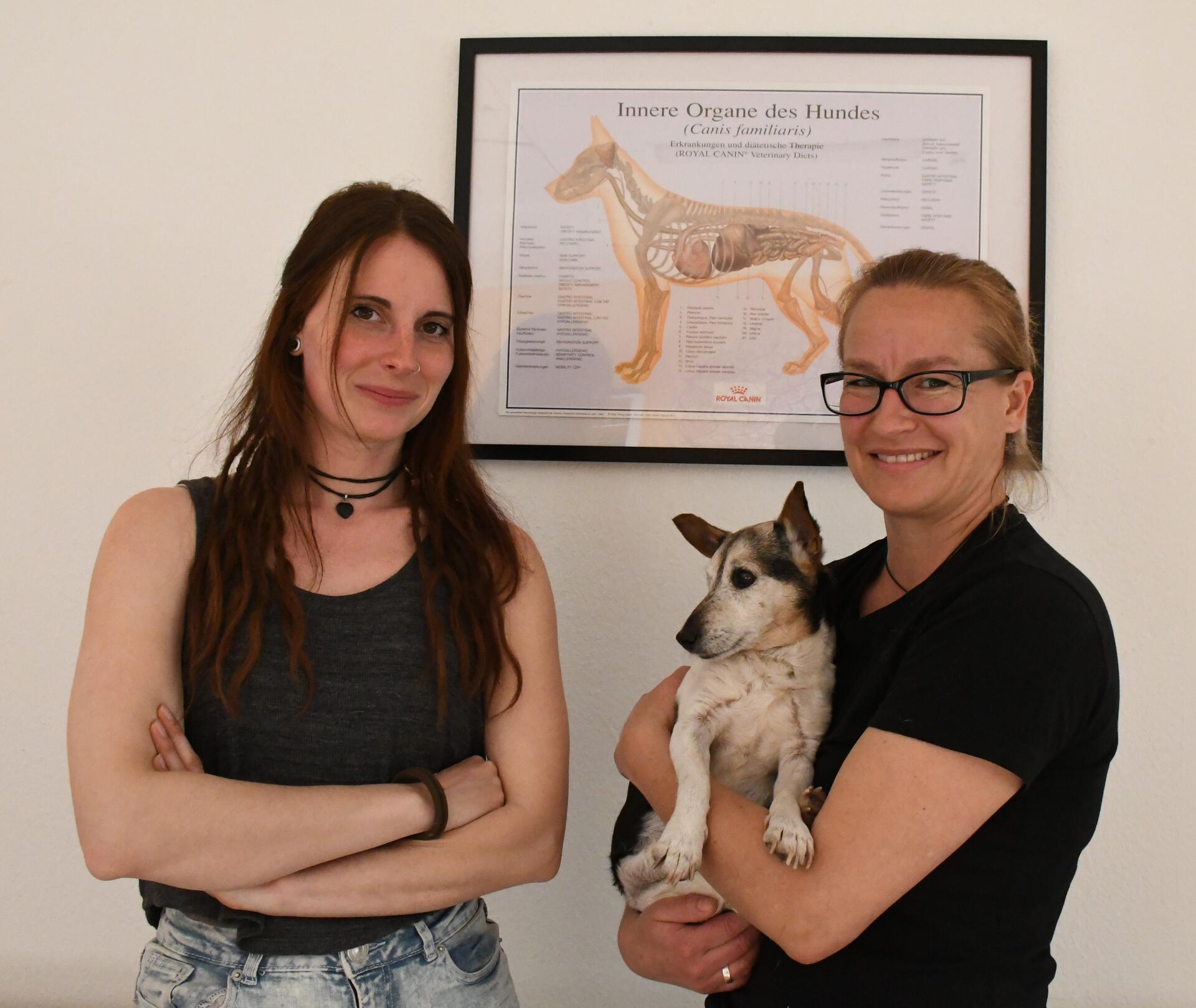 Zwei Frauen lächeln, die Frau rechts hält einen Hund auf ihren Armen. Im Gesundheitszentrum für Hunde: Sahra-Lena Jaudzin (links) und Anja Aßhauer mit Hündin Lili, der Assistentin auf vier Pfoten.