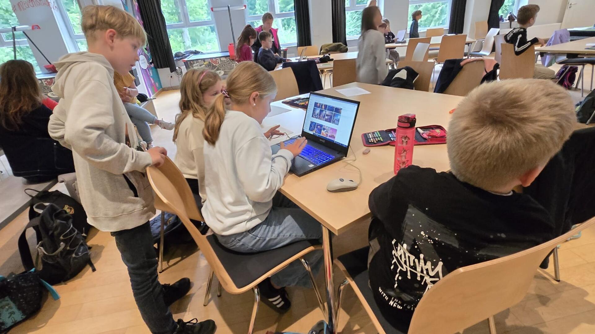 Schüler sitzen in einem Schulraum vor Tablets. 