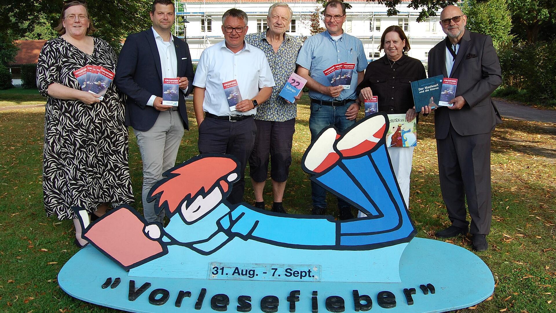 Männer und Frauen haben sich mit Programmheften in der Hand zu einem Gruppenfoto aufgestellt.