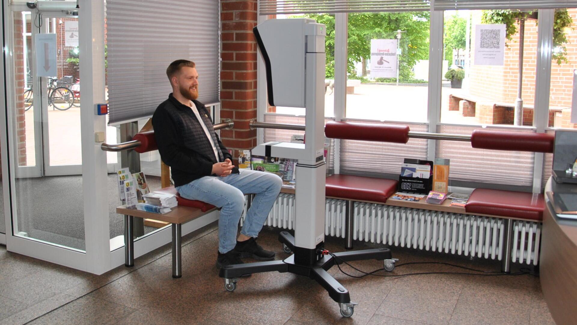 Im Zevener Rathaus können Bürger jetzt digitale Passbilder machen lassen: Verwaltungsmitarbeiter Julian Selbach und seine Kollegen aus dem Bürgerservice kennen sich mit dem neuen Gerät im Foyer schon gut aus.