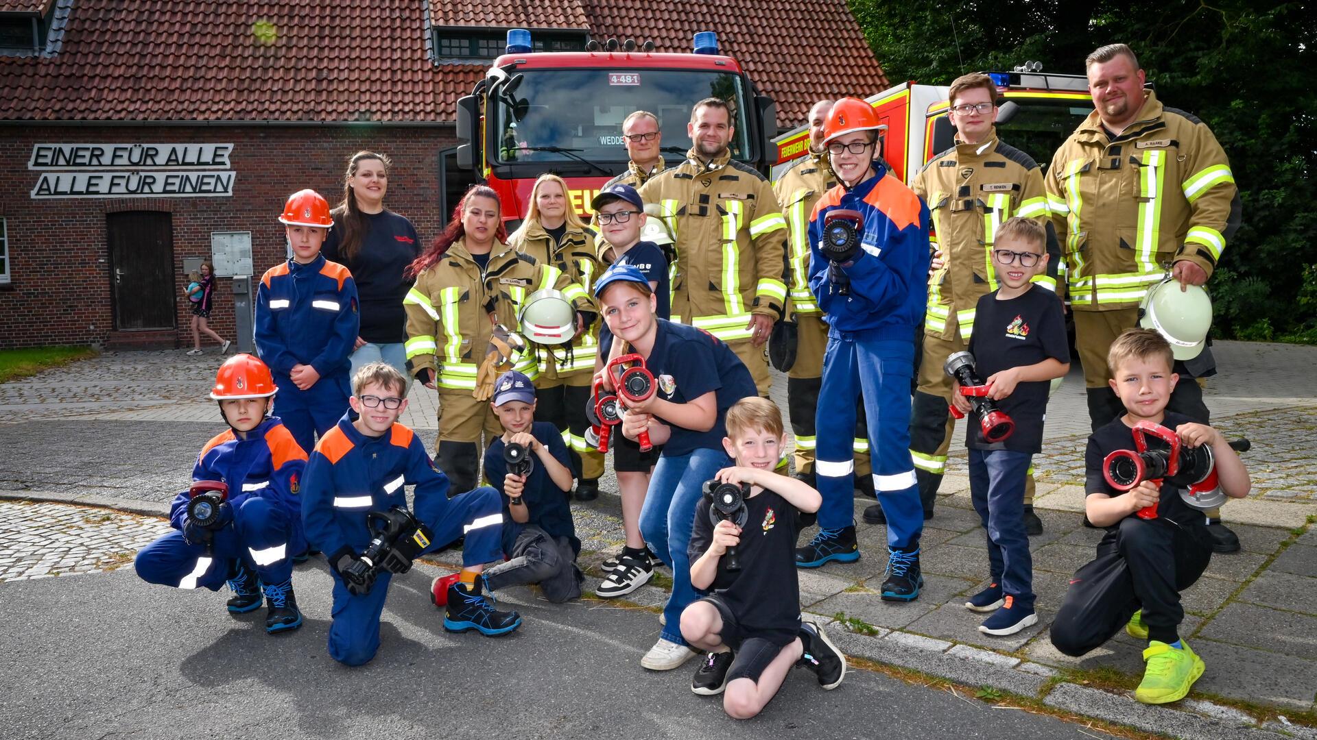 Kinder und Erwachsene vor einem Feuerwehrhaus.