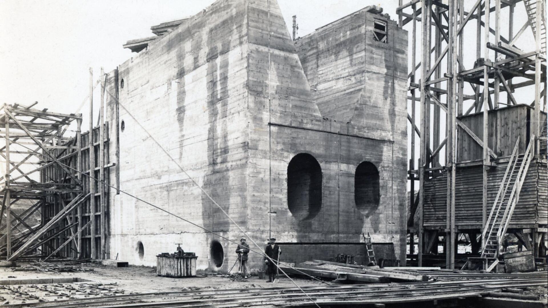 Ein aus Beton gegossenes Bauteil der Schleuse. Davor stehen zwei Männer.