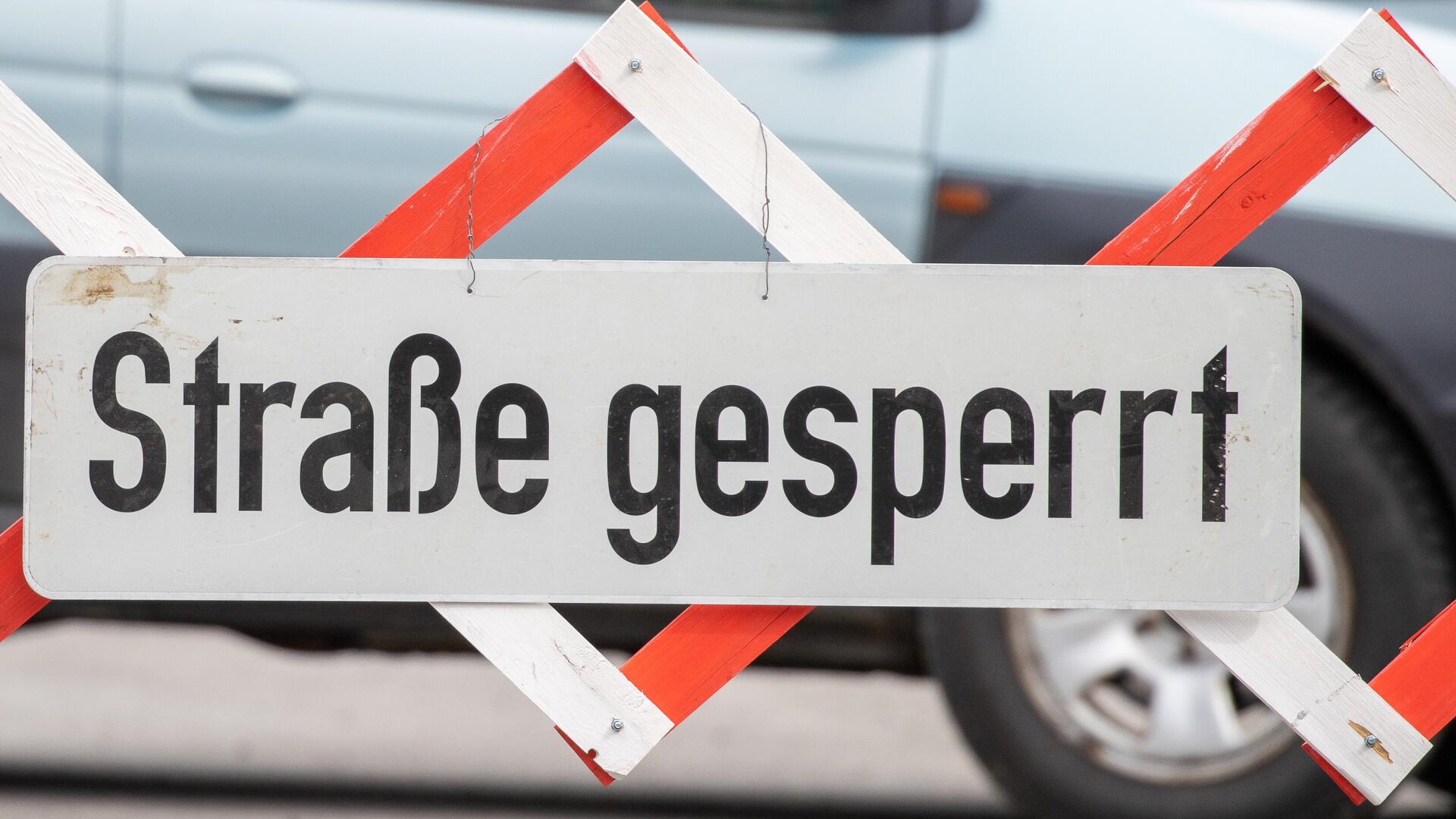 An einer Straßensperre ist ein Schild mit der Aufschrift „Straße gesperrt“ angebracht. 