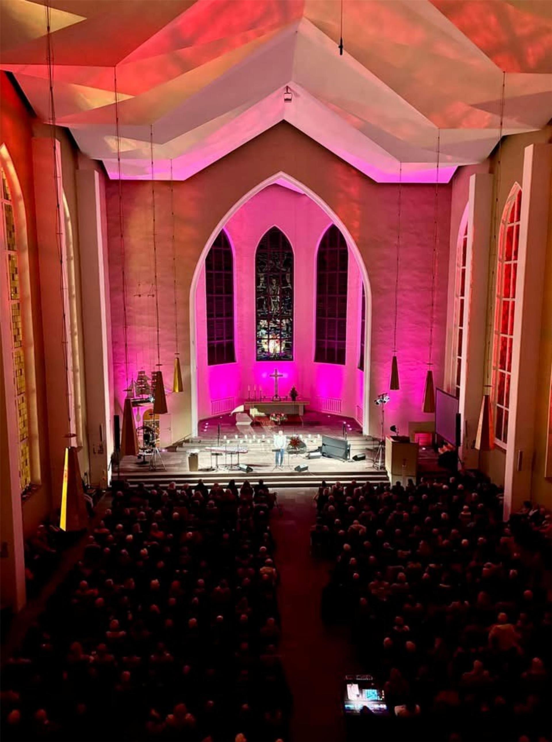 eine Kirche, vor dem Altar sitzen viele Leute