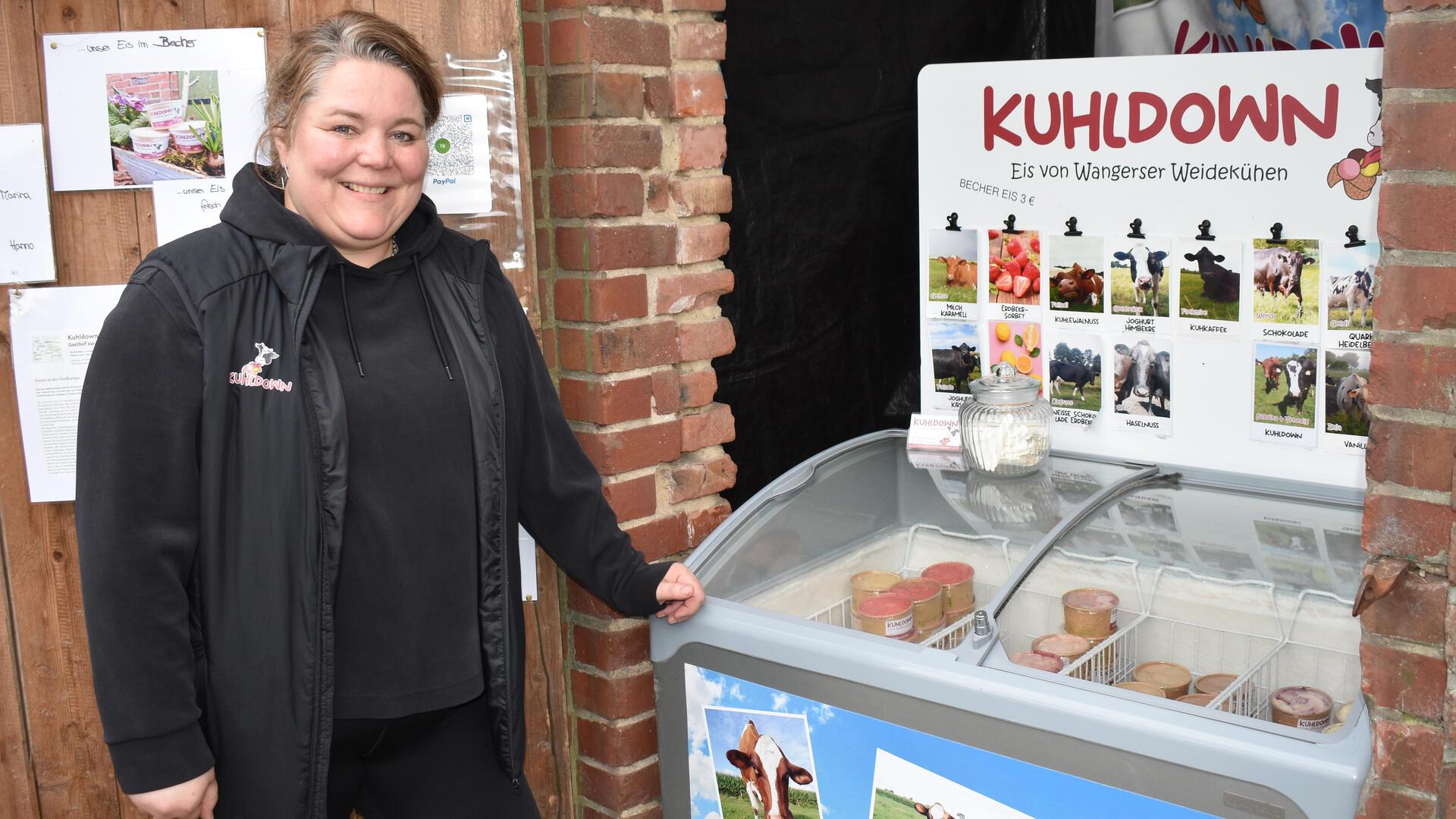 Eine Frau steht neben einer Eistruhe.