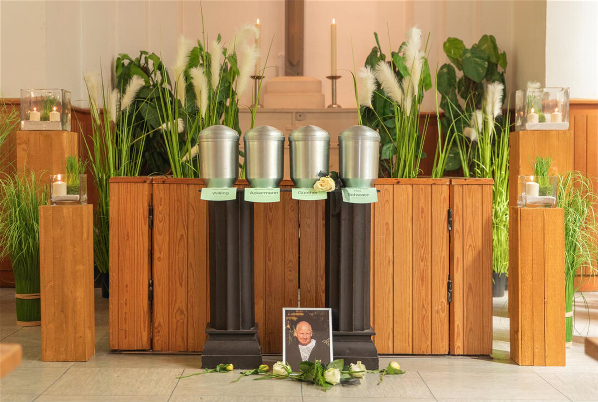 Vier Urnen vor einem Altar. Davor das Foto eines Verstorbenen.