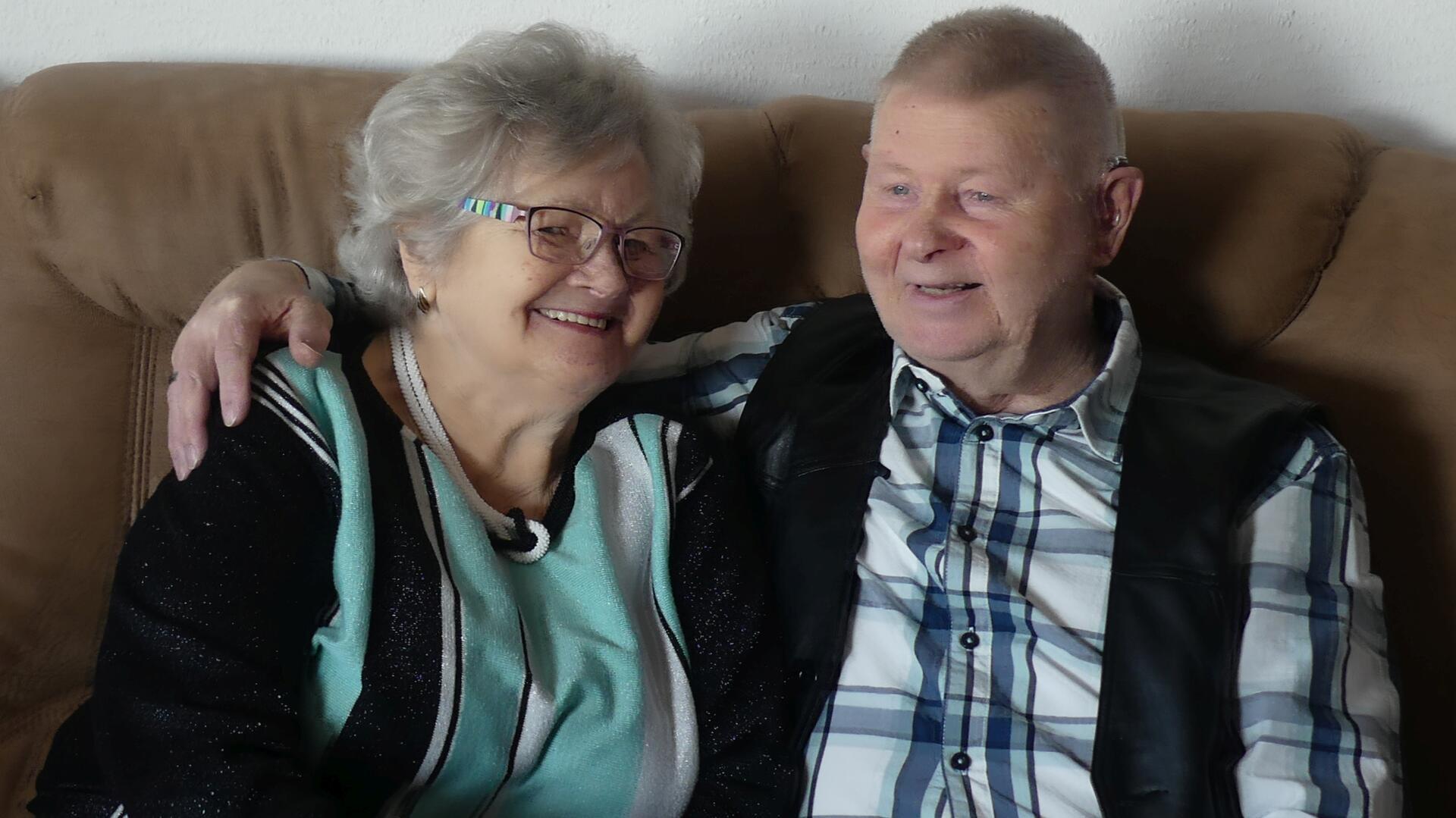 Ein Mann und eine Frau sitzen auf einem Sofa und strahlen.