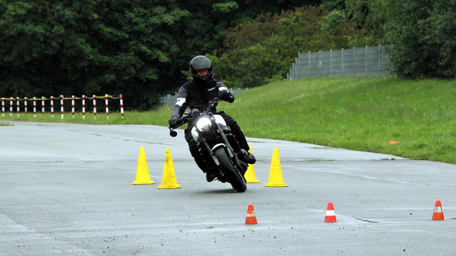 Ein Motorradfahrer legt sich auf regennasser Fahrbahn in die Kurve.