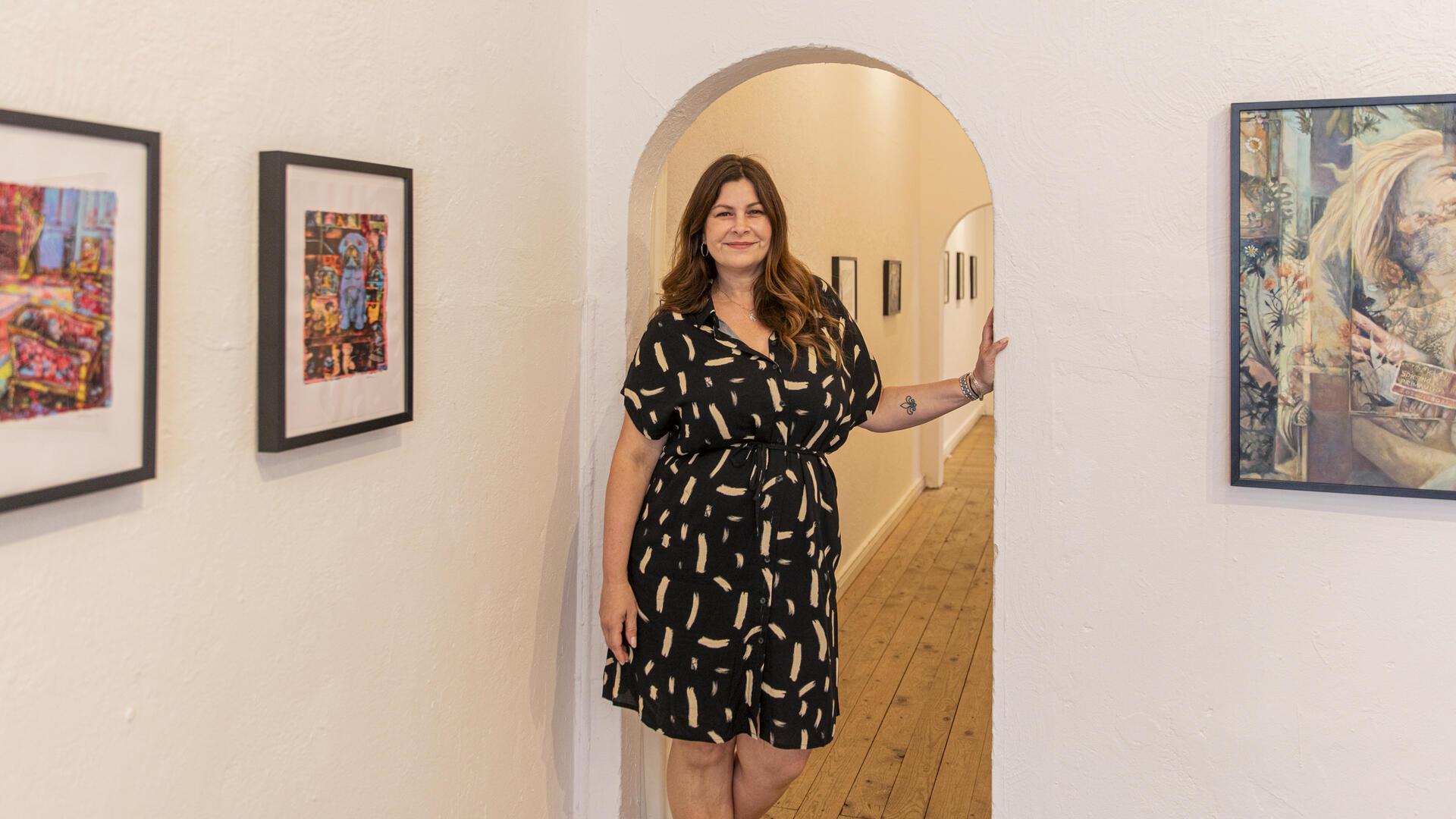 Künstlerin Jessica Russo Scherr steht in einer Galerie Bilder hängen an den Wänden