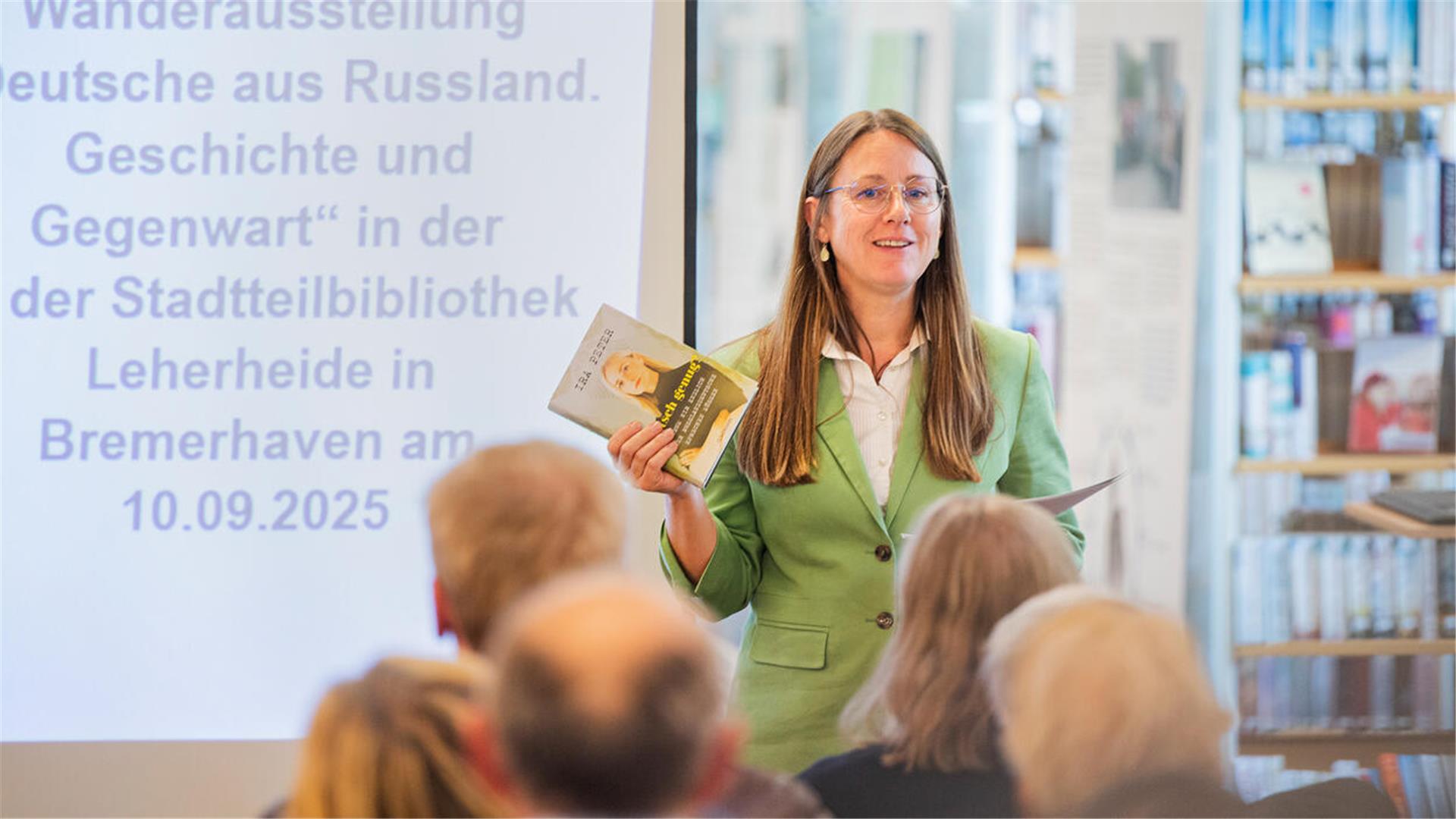 Eine Frau spricht vor Menschen in einer Bibliothek. 