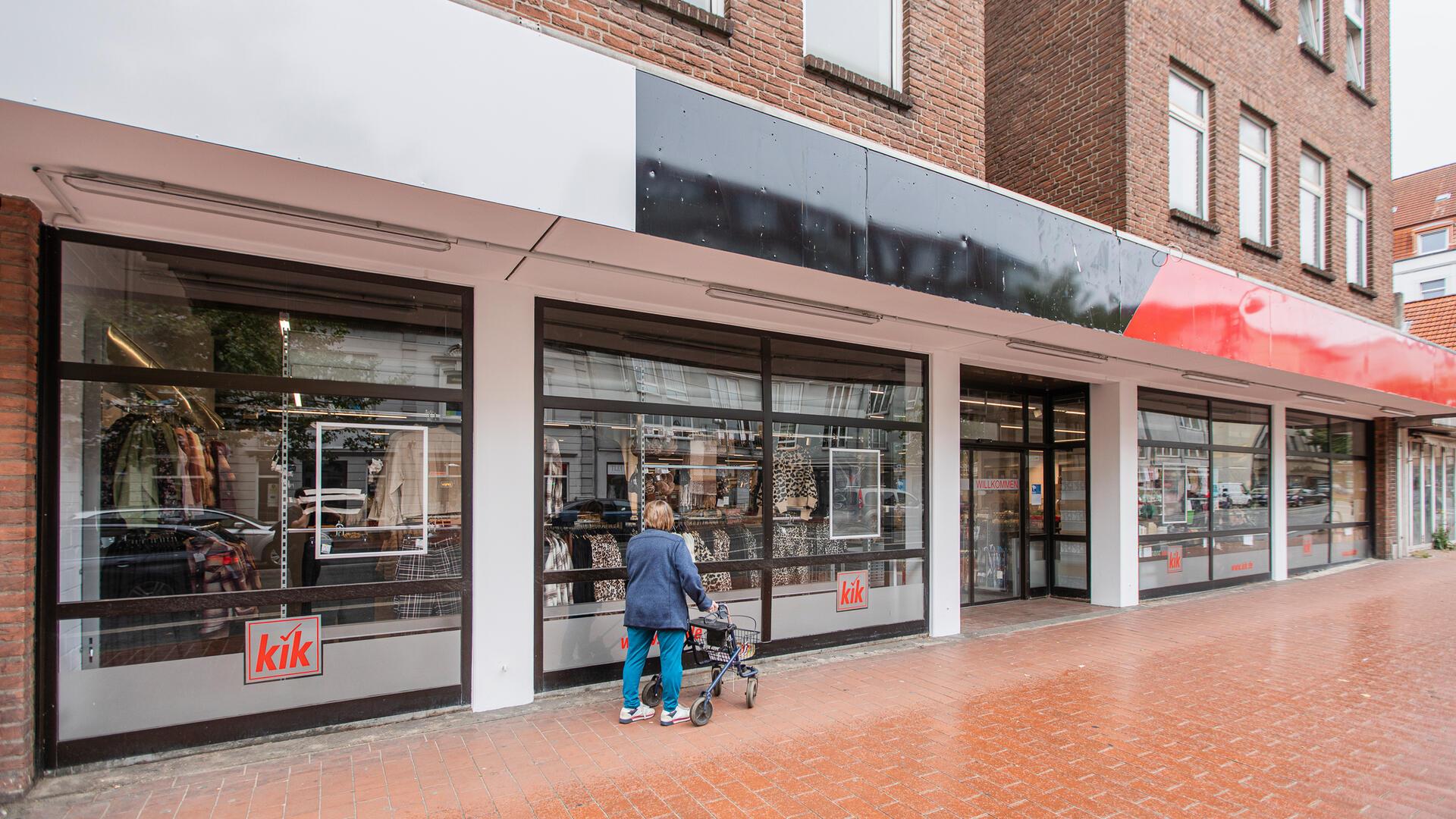eine KiK-Filiale vor der Eröffnung, eine Frau mit Rollator wirft bereits einen Blick ins Schaufenster