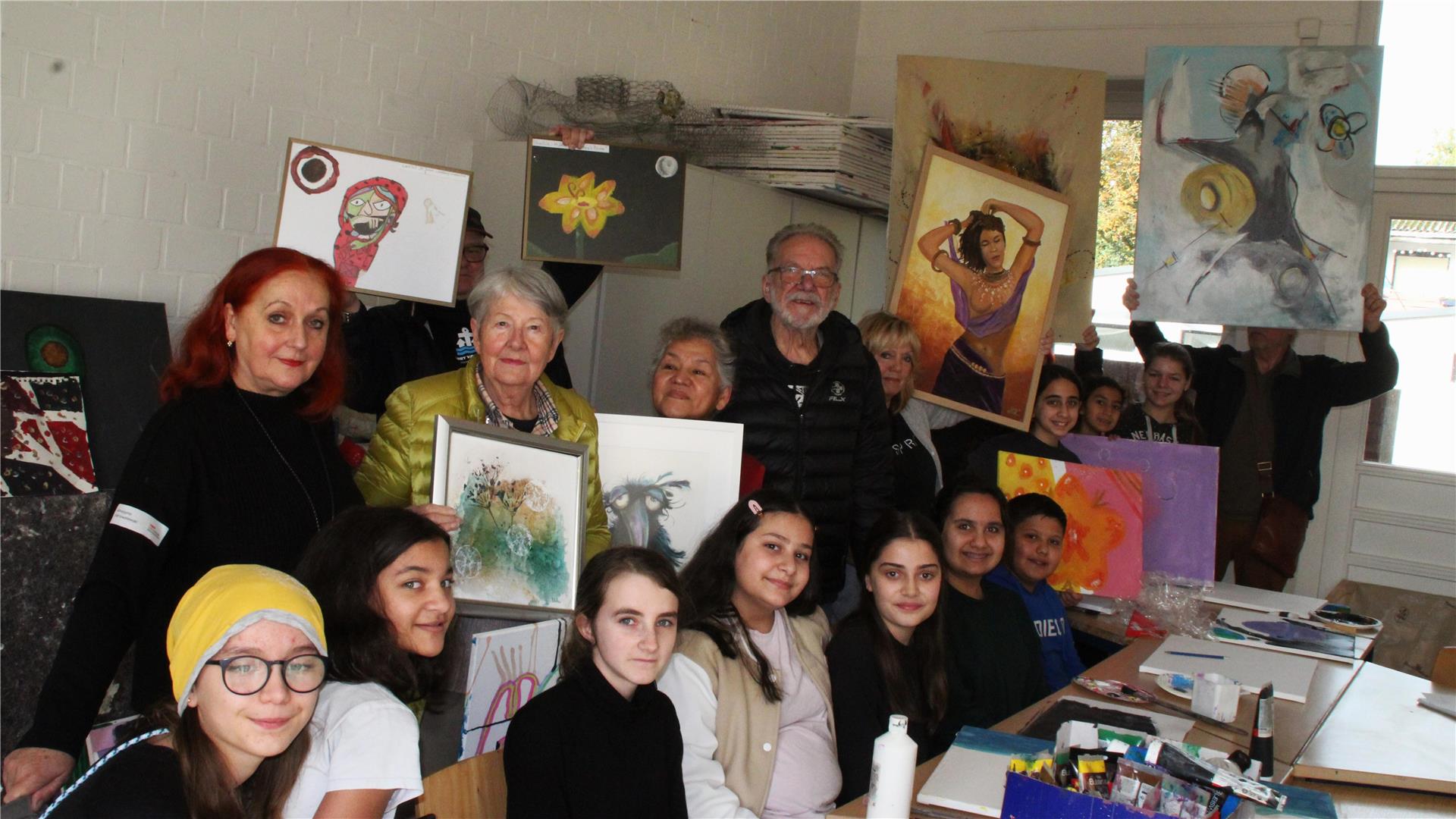 Schülerinnen halten ihre Bilder hoch, Erwachsene gucken zu