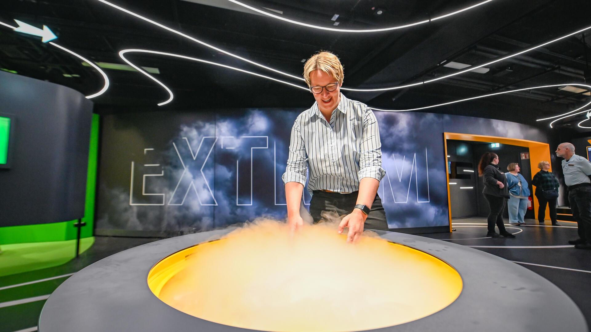 Die Geschäftsführerin des Klimahauses, Ingrid Hayen, zeigt ein Exponat der Ausstellung Wetterextreme.