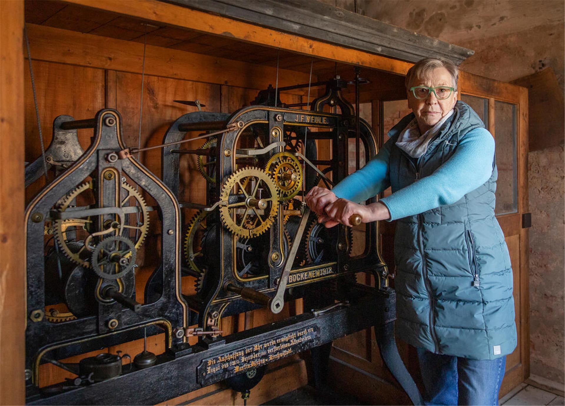 Küsterin Käte Heins am mechanischen Uhrwerk der Kirchwistedter Kirche: Mit der Kurbel bringt sie die Uhr zum Laufen.