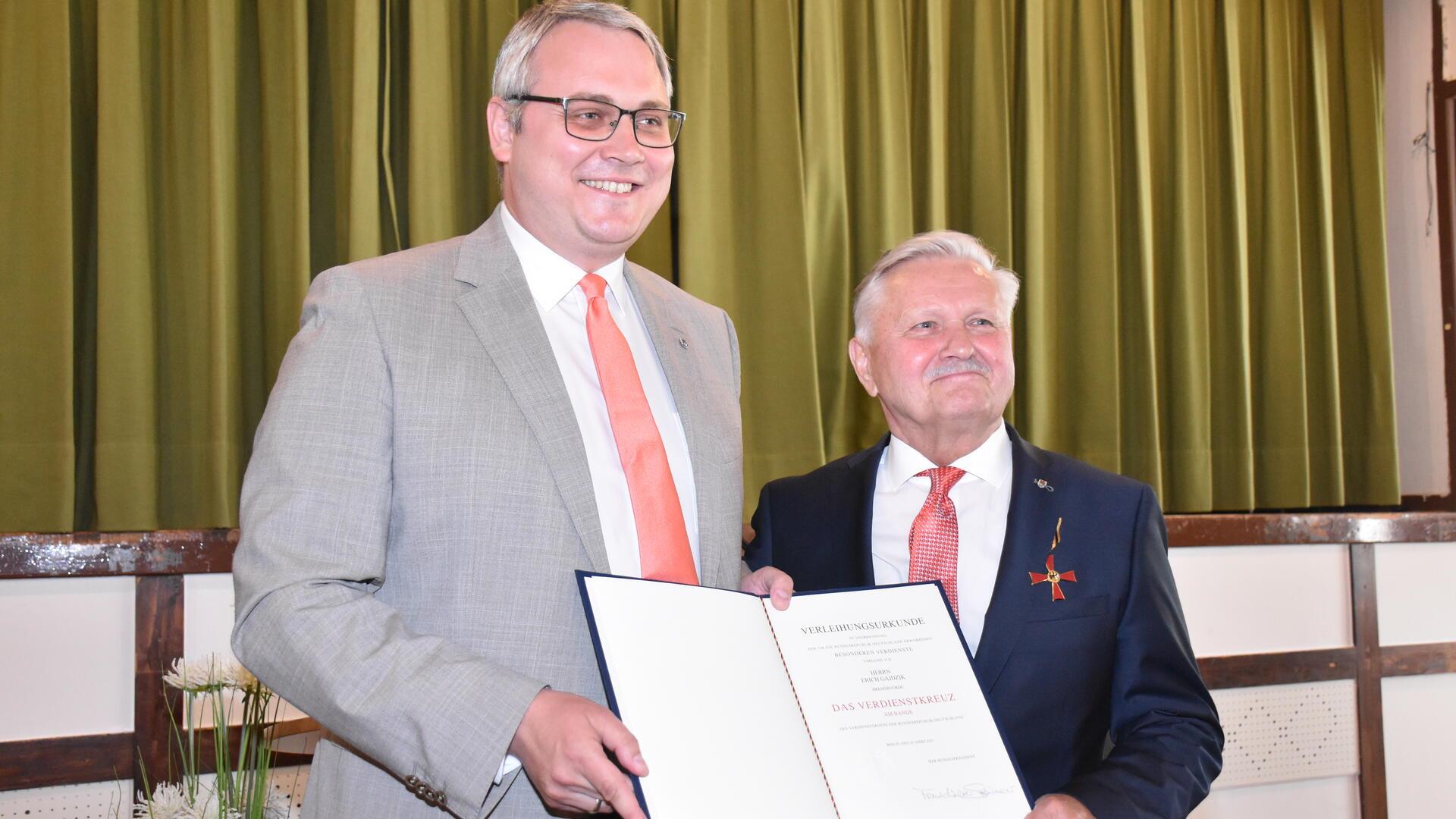 Landrat Marco Prietz (links) überreichte Erich Gajdzik die von Bundespräsident Frank-Walter Steinmeier unterzeichnete Urkunde und steckte ihm den Verdienstorden an. 