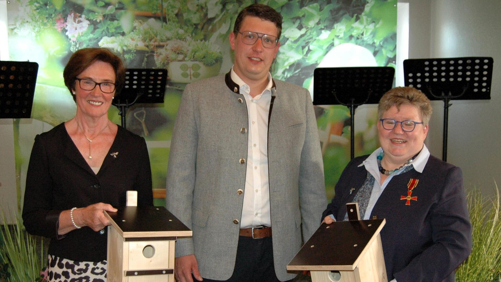 Ein Mann und zwei Frauen gucken in die Kamera.