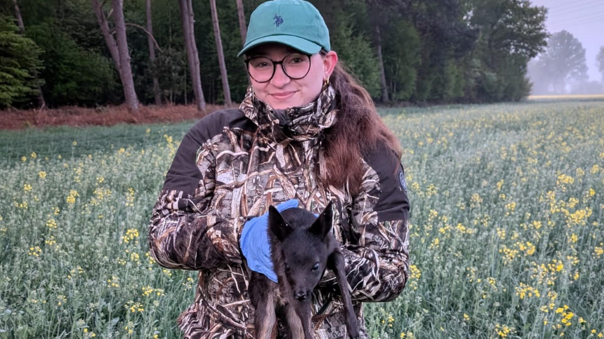 Lea Schlotmann findet ein nicht so häufiges schwarzes Rehkitz auf der Fläche und bringt es gemeinsam mit dem anderen Rehkitz in Sicherheit.