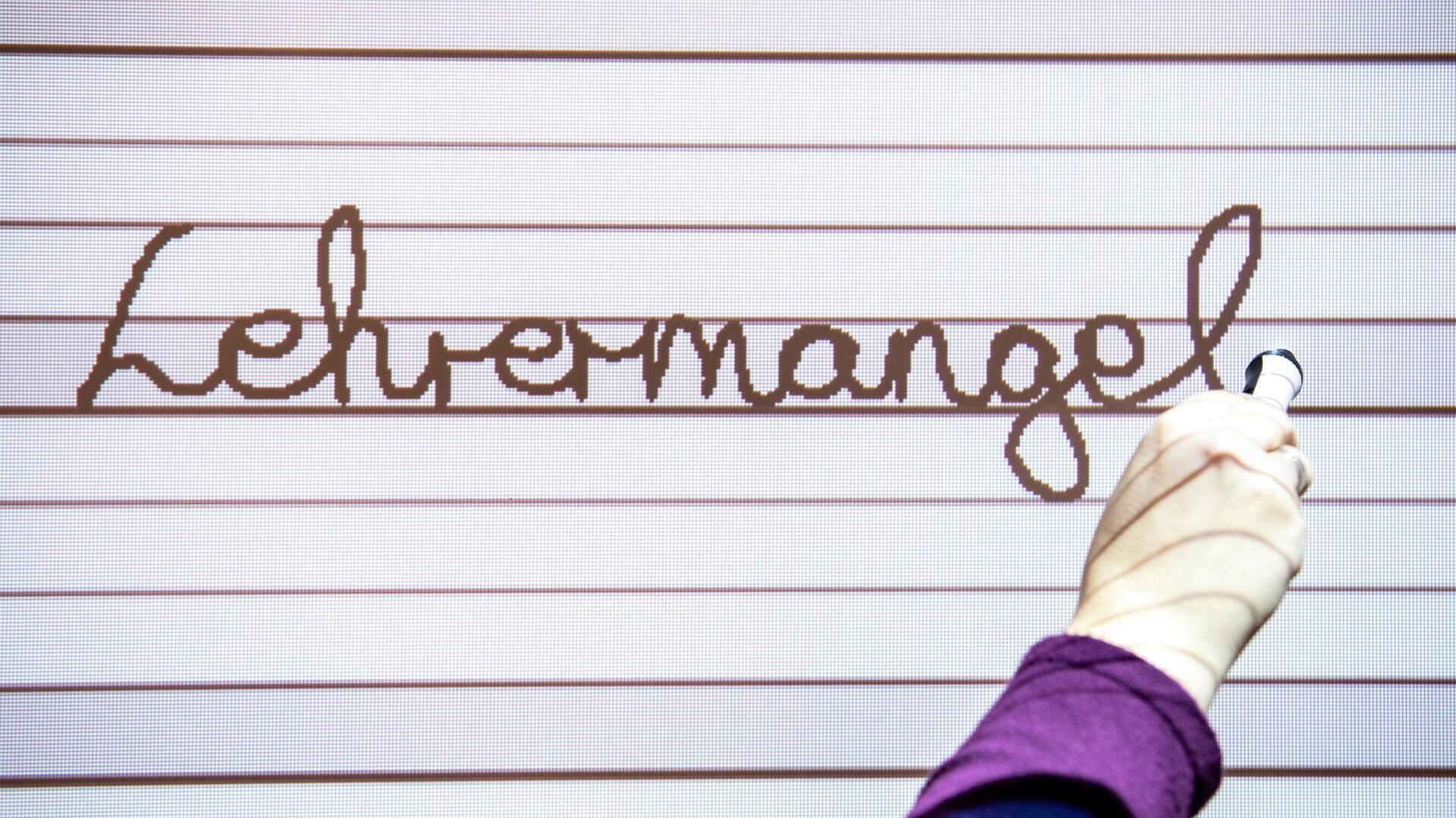 An ein Whiteboard wird der Schriftzug "Lehrermangel" geschrieben.